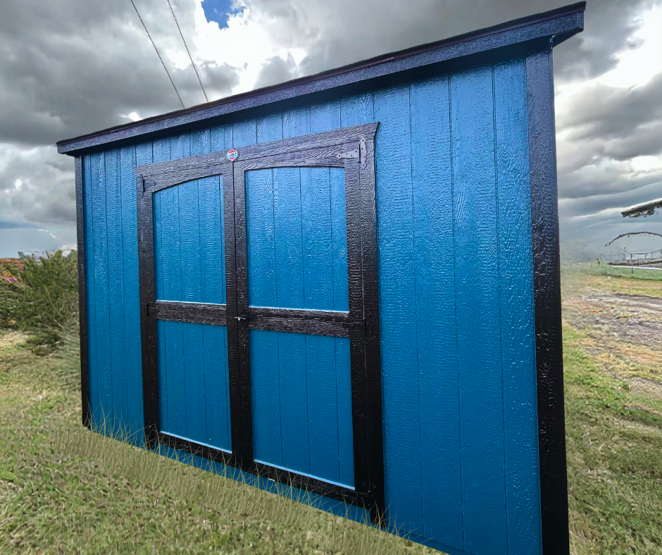 blue shed with black trim on grass with grey clouds above