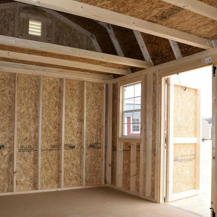 Interior of a construction site with unfinished wooden framing, a window, and a door leading outside.