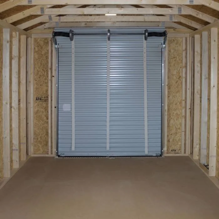 Interior of a wooden shed with a metal roll-up door on one wall.