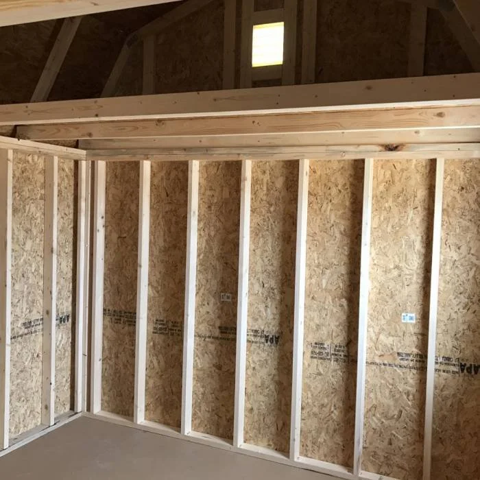 Interior of a building under construction with wooden framing and OSB wall sheathing.