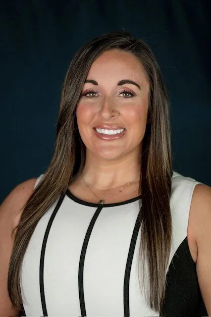 A woman sitting on a park bench near a body of water during the daytime.