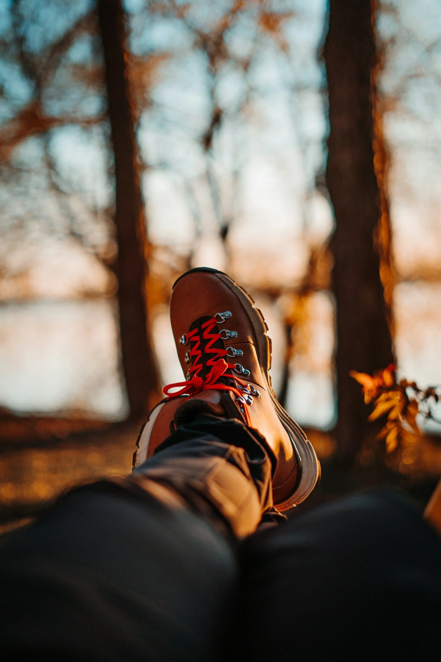 Hiking boots in foreground, water and trees in blurred in background