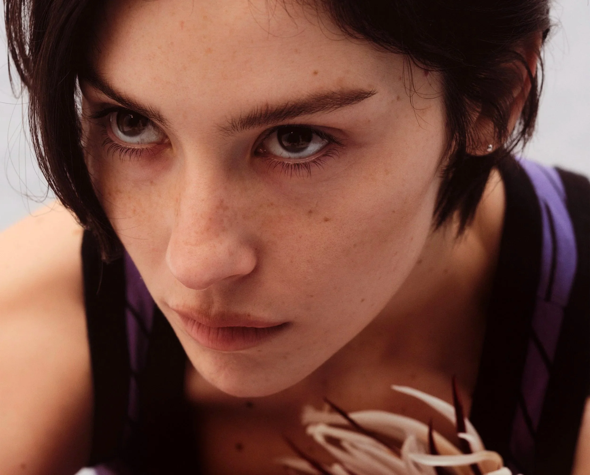 Close-up of Gracie Abram's face, focusing on the eyes, forehead, and part of the nose, with short dark hair and dark eyes. The artwork cover for new album, 'Daughter From Hell'.