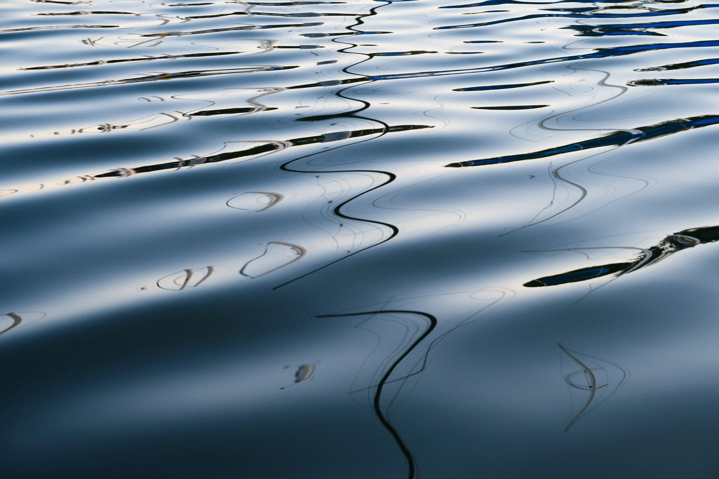 Calm water surface with gentle ripples and reflections of the sky and surrounding environment.