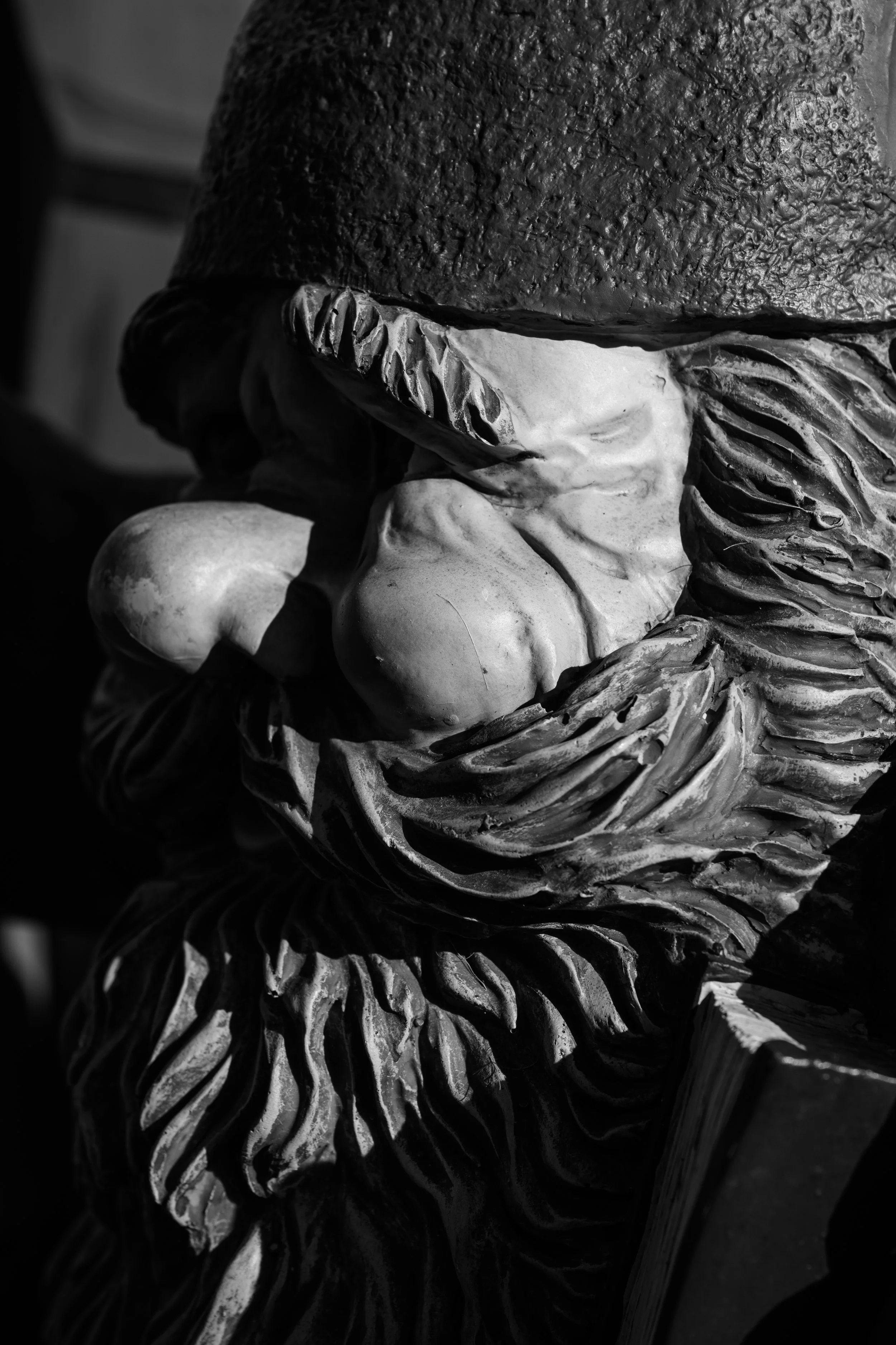 Close-up of a black-and-white sculpture depicting a bearded man with a hat, with intricate detailing in the beard and facial features.