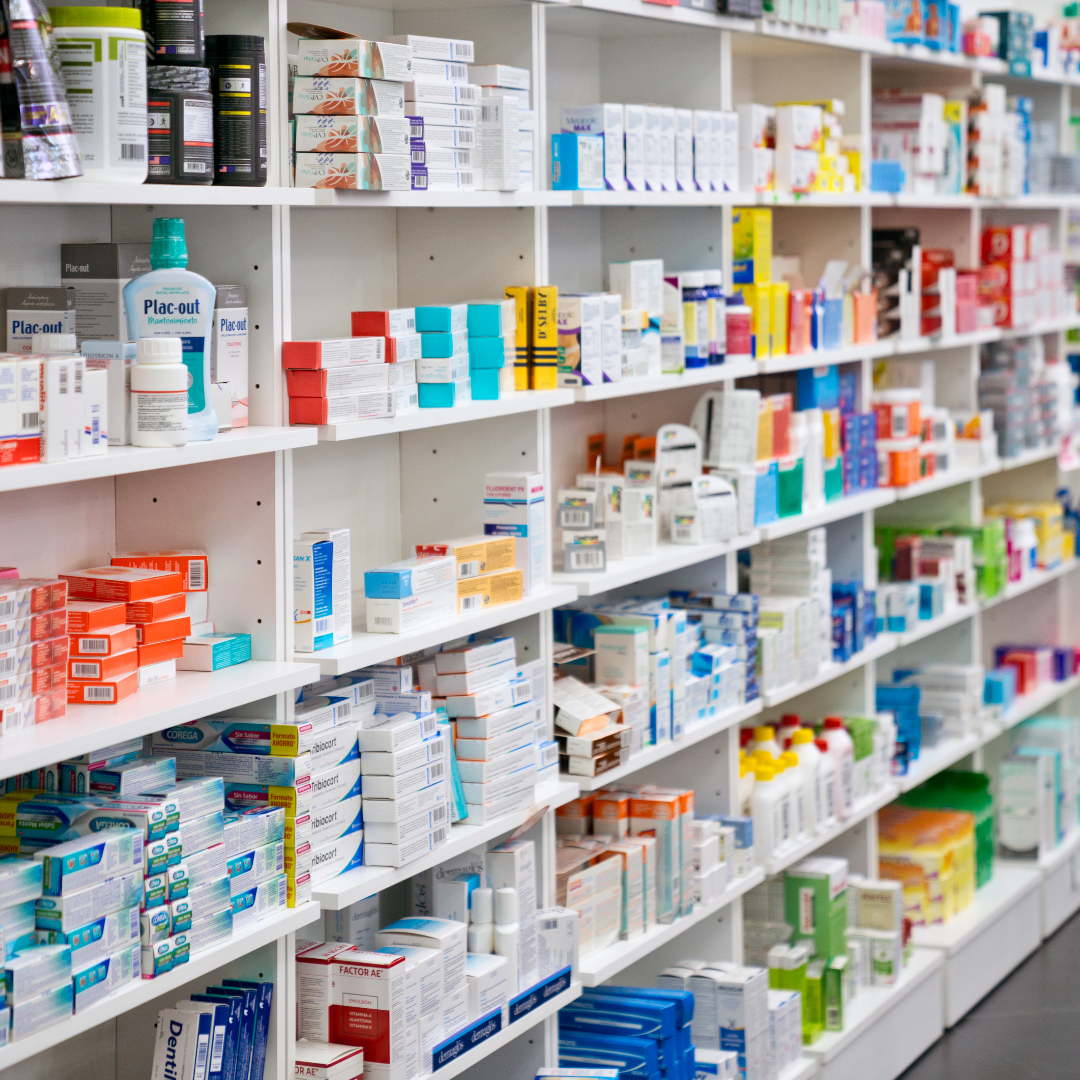 Shelves stocked with various boxes and bottles of medications and healthcare products in a pharmacy.