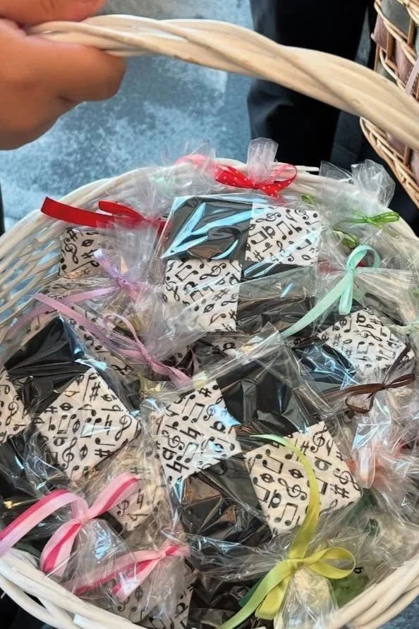 A white basket filled with decorated cookies wrapped in clear plastic and tied with pastel-colored ribbons.