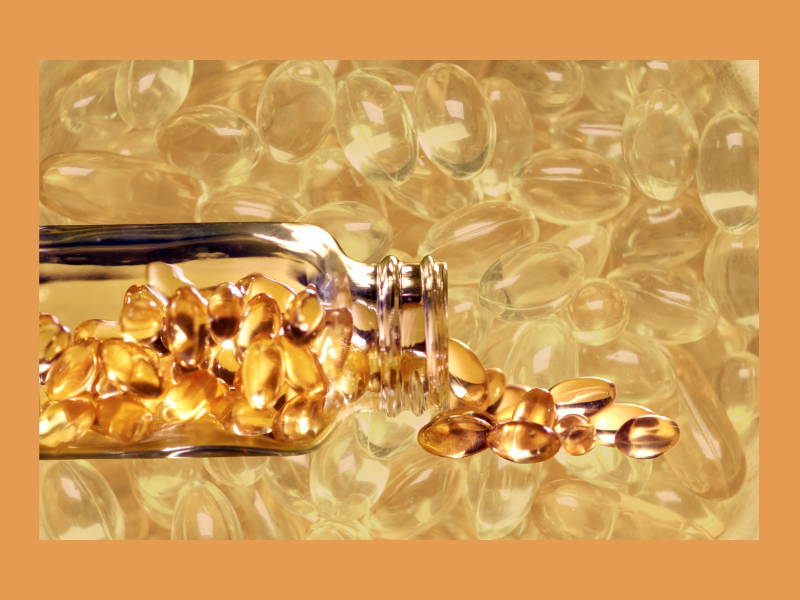 Vitamin E capsules pouring out of a bottle.