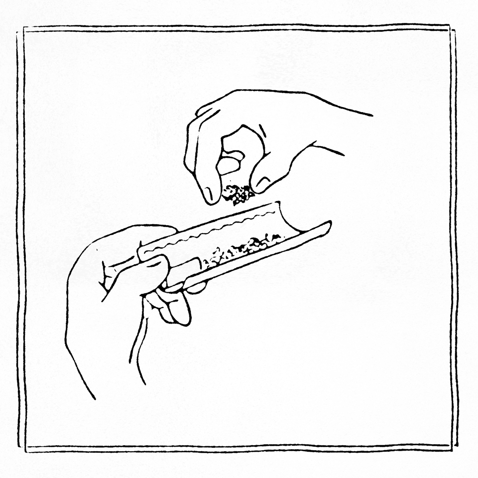 Two hands handling rolling paper and tobacco.