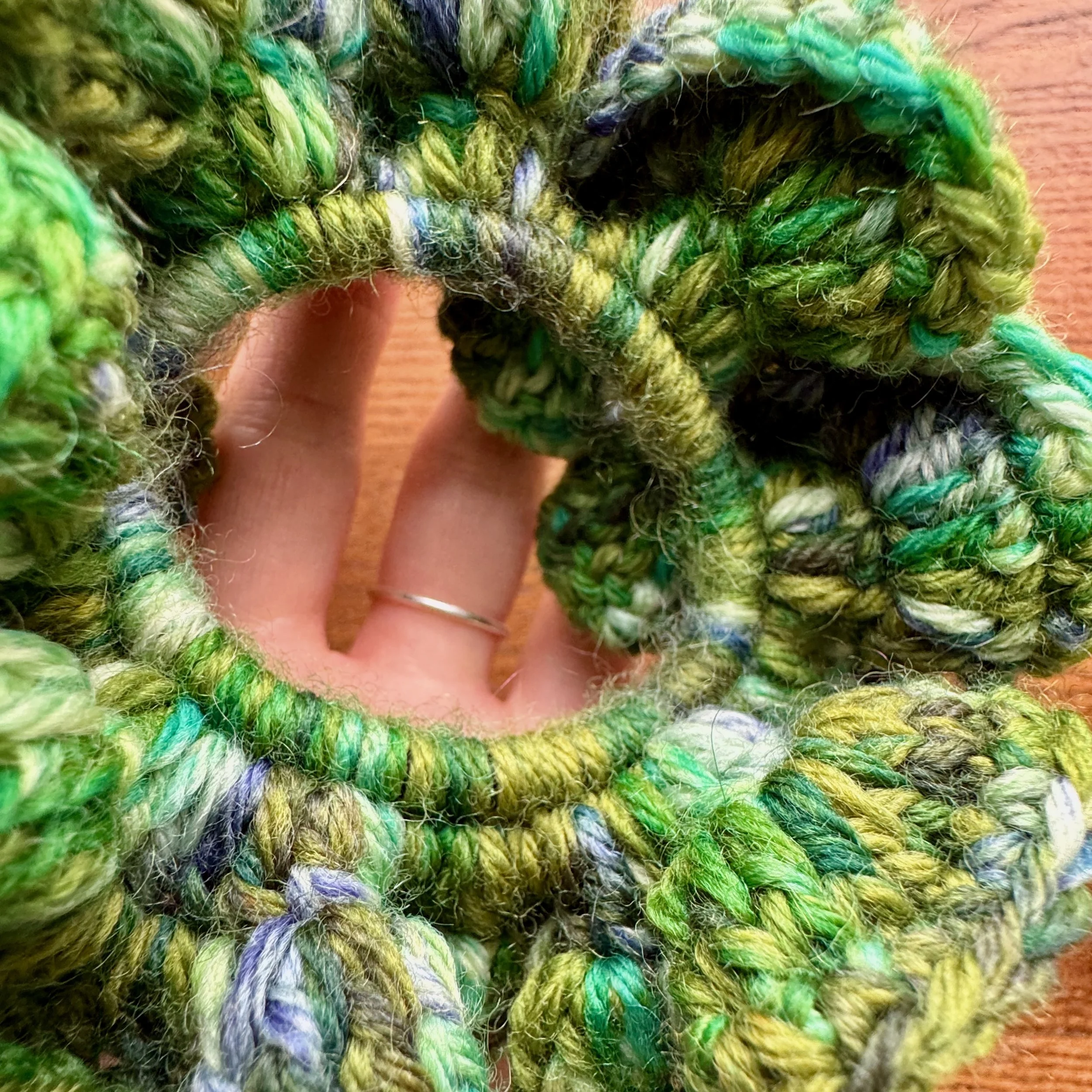 A close up view of a multi green crochet ruffle scrunchie