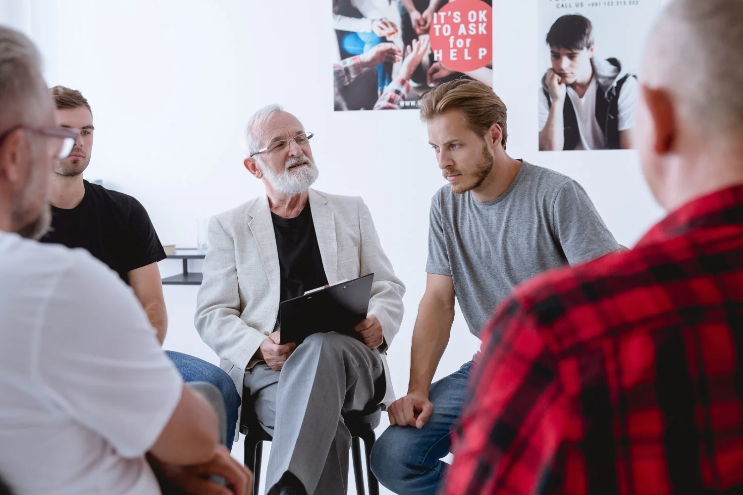 A diverse group of six people participating in a support group discussion.