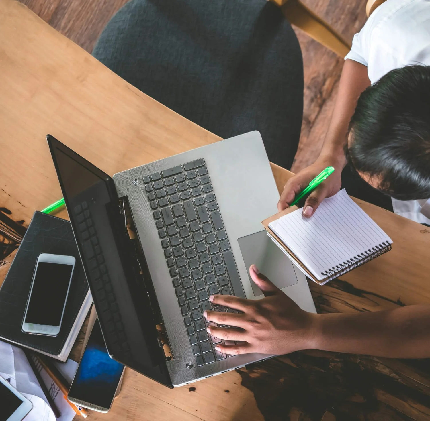 Overhead view of a person using a silver laptop at a wooden desk