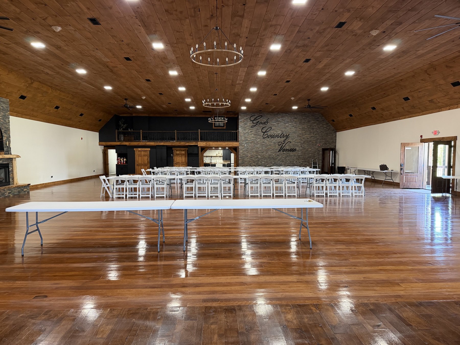 Spacious reception hall at God's Country Venue in Oak Hill, Ohio, featuring polished wood floors, chandeliers and flexible seating for weddings and events.