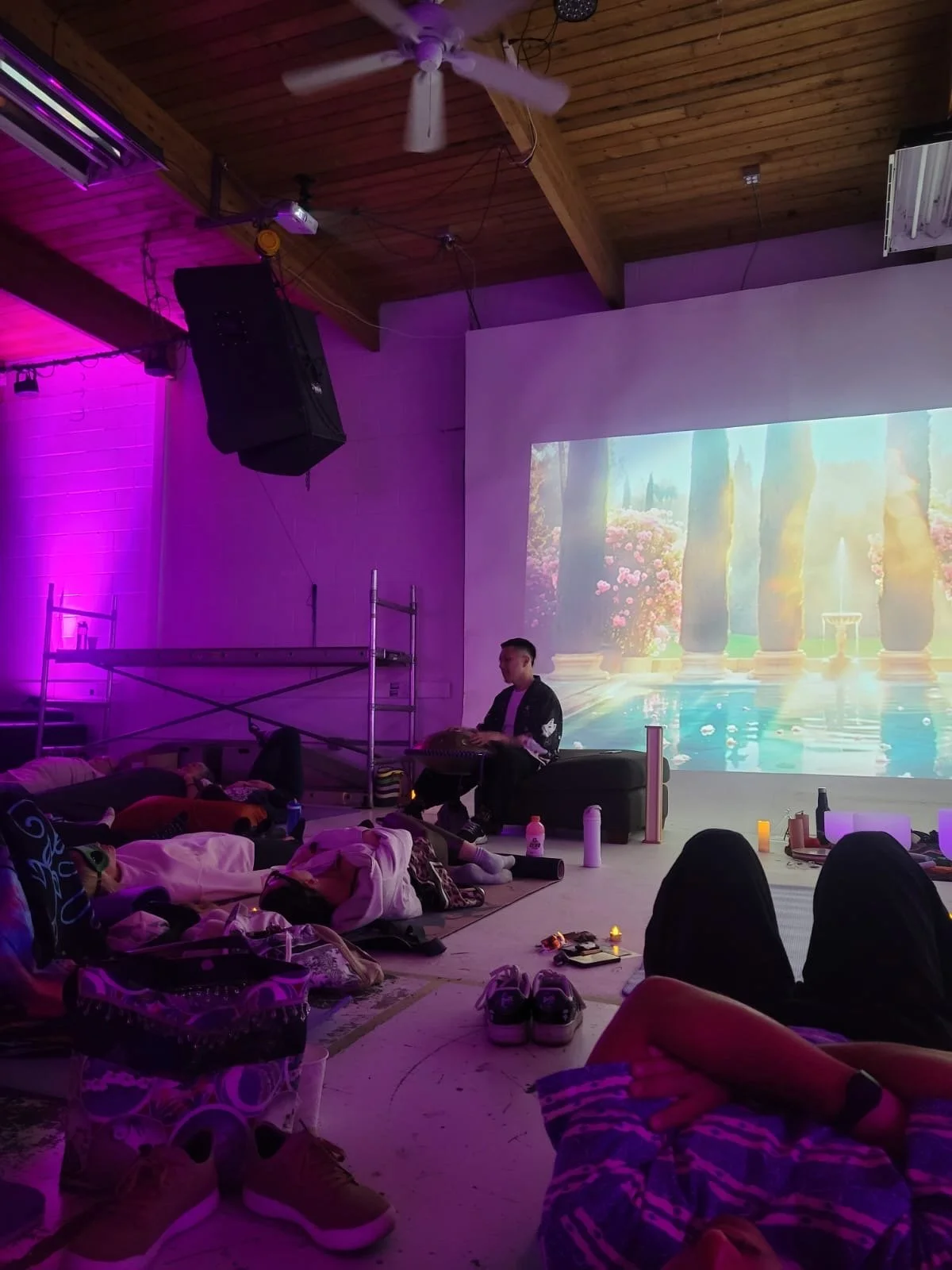 Alex Ma from Solar Soul Circle playing handpan in Gastown, Vancouver, BC. With many guests lying down enjoying a public sound healing session. Relaxing in the purple lighting and gorgeous atmosphere created at this event.