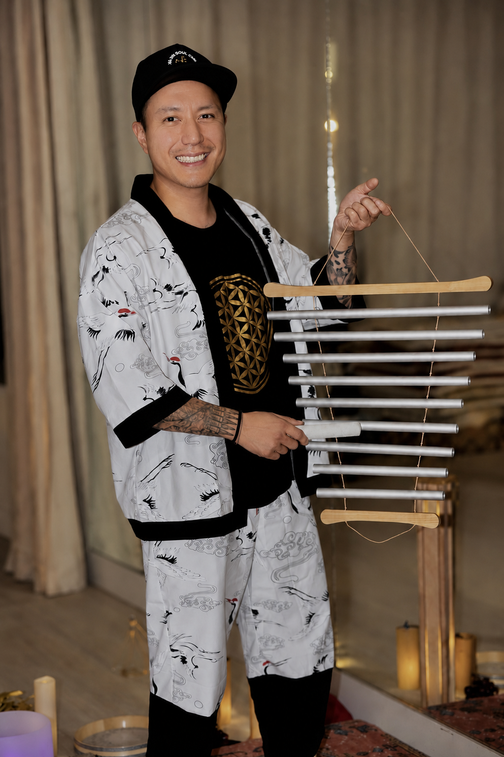 Alex Ma from Solar Soul Circle with a big smile, holding chimes at a sound bath within Love & Peace Studio in Kitsilano