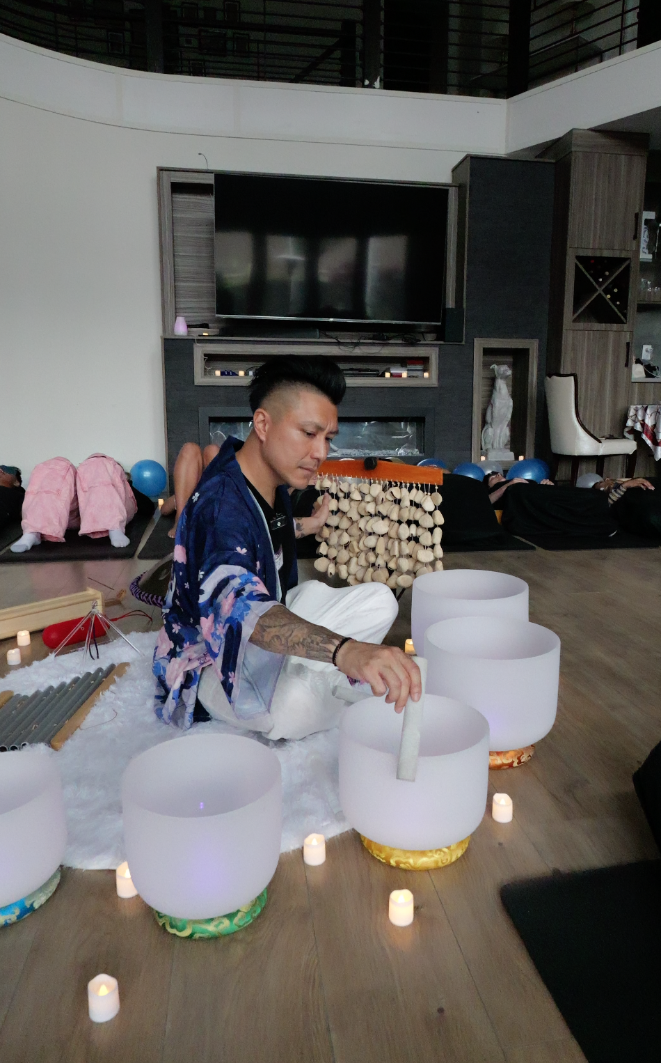Sound bath facilitator Alex Ma playing the crystal sound bowls during a soundbath in Surrey for a private birthday party 