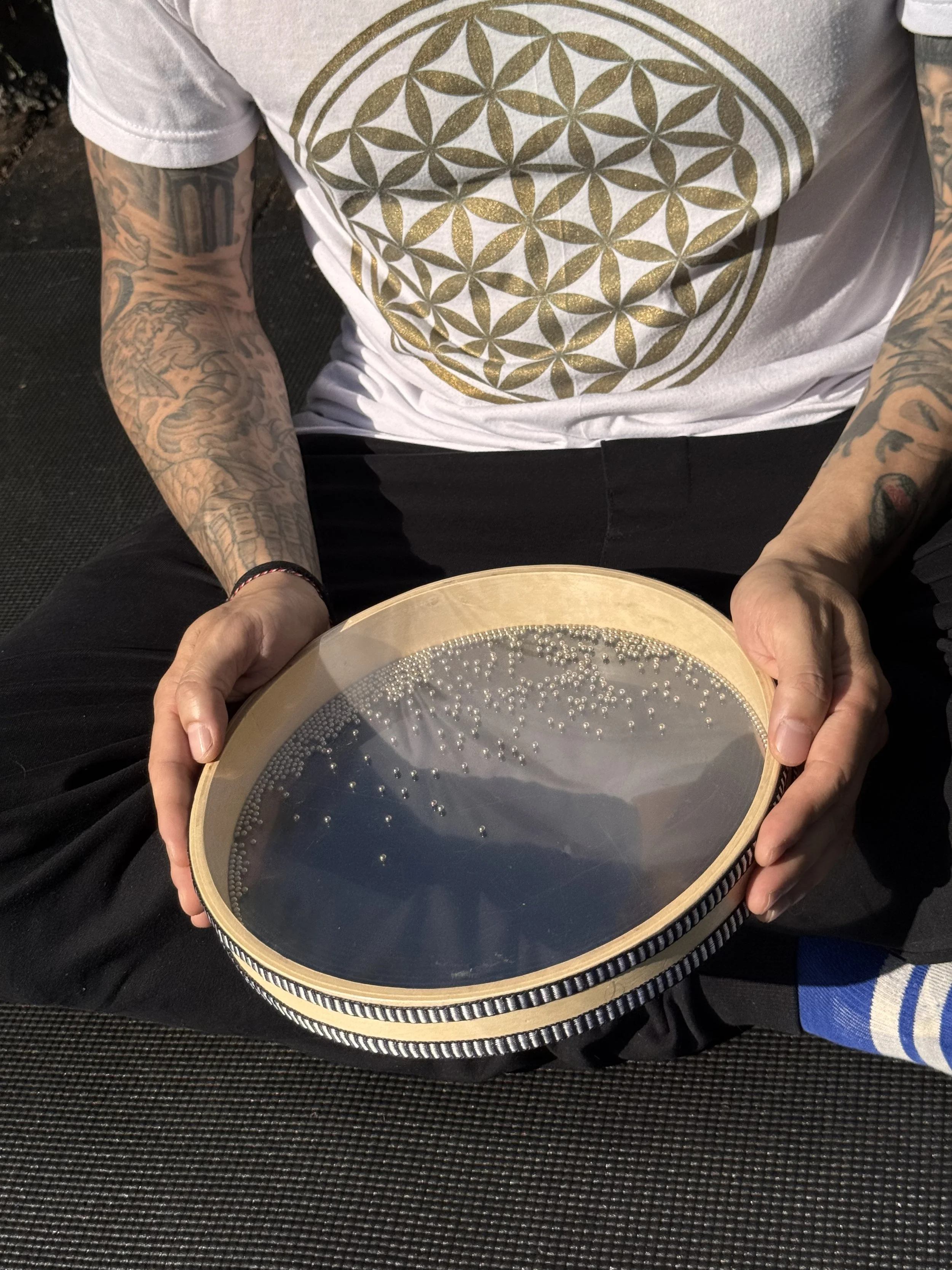 The ocean drum being played by Alex Ma from Solar Soul Circle outdoors while sitting cross legged.