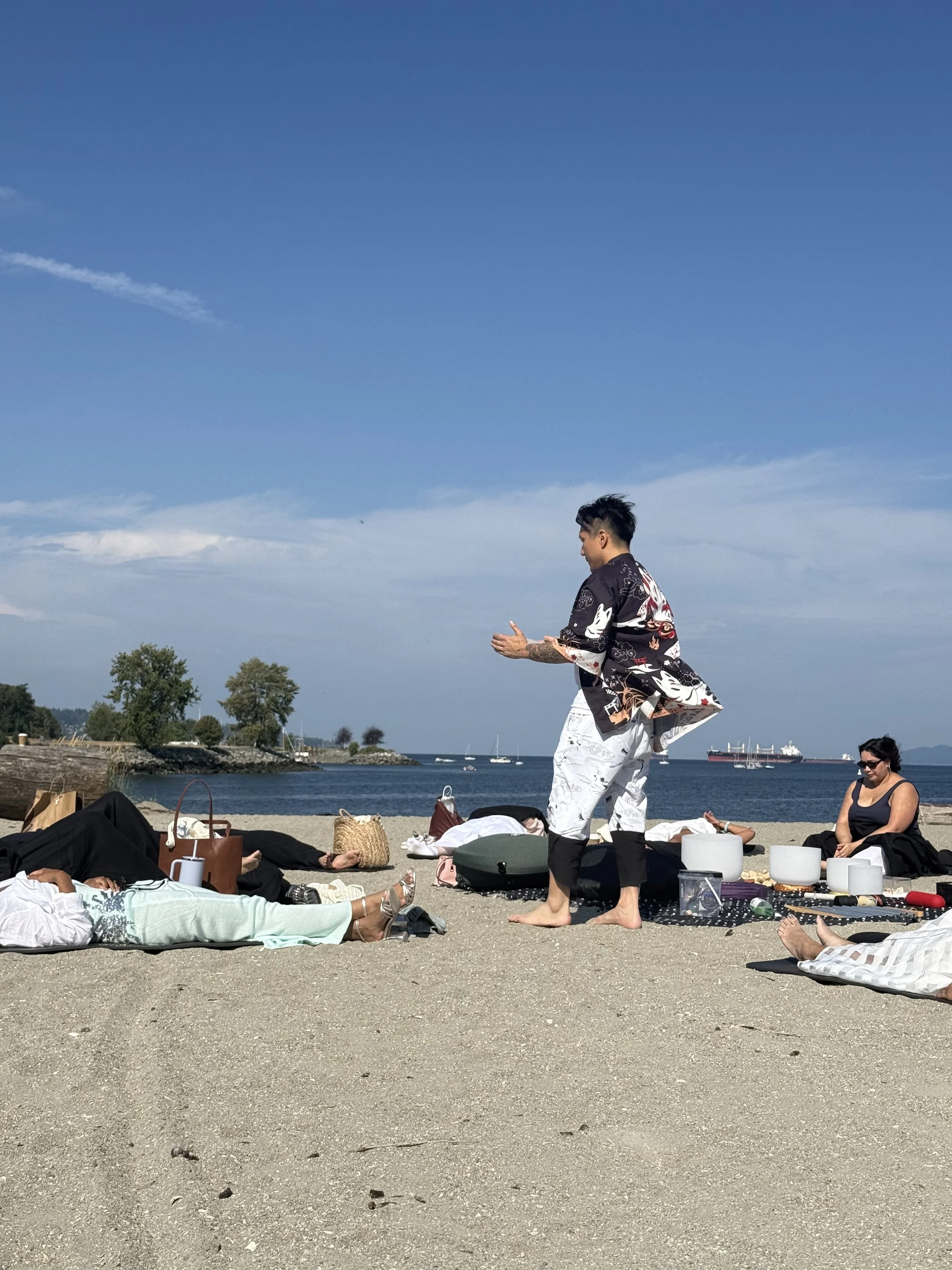 Alex playing the ocean drum during a beach sound bath in Vancouver