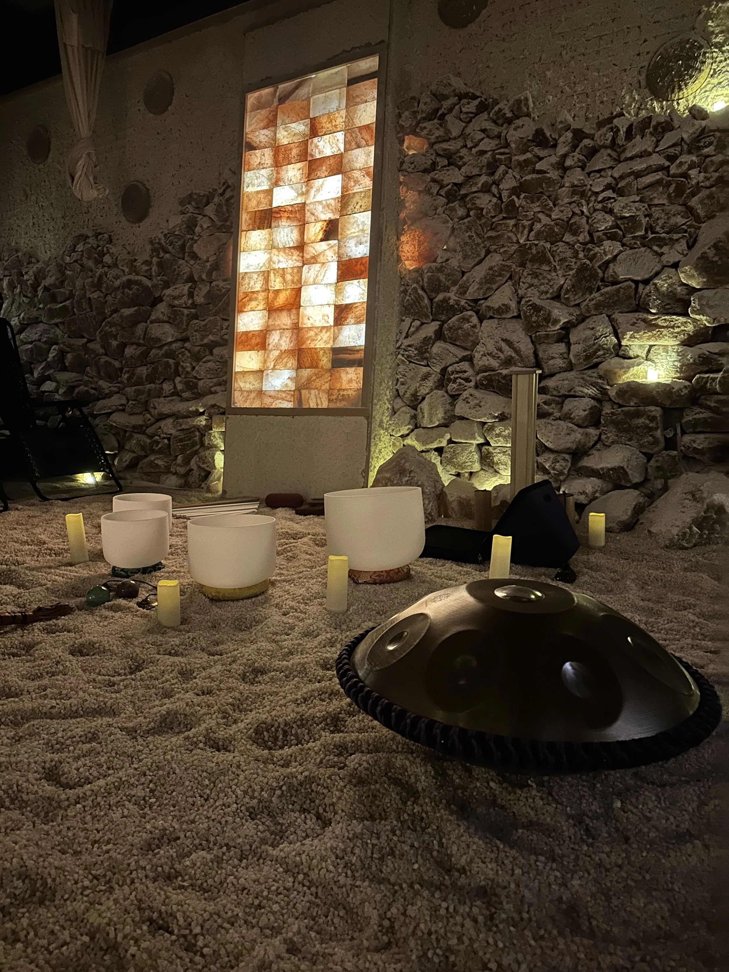 A Solar Soul Circle instrument layout of handpan, crystal singing bowls, rain stick and other resonant instruments for a sound bath in North Vancouver at the Saltwonder Himalayan Salt Cave