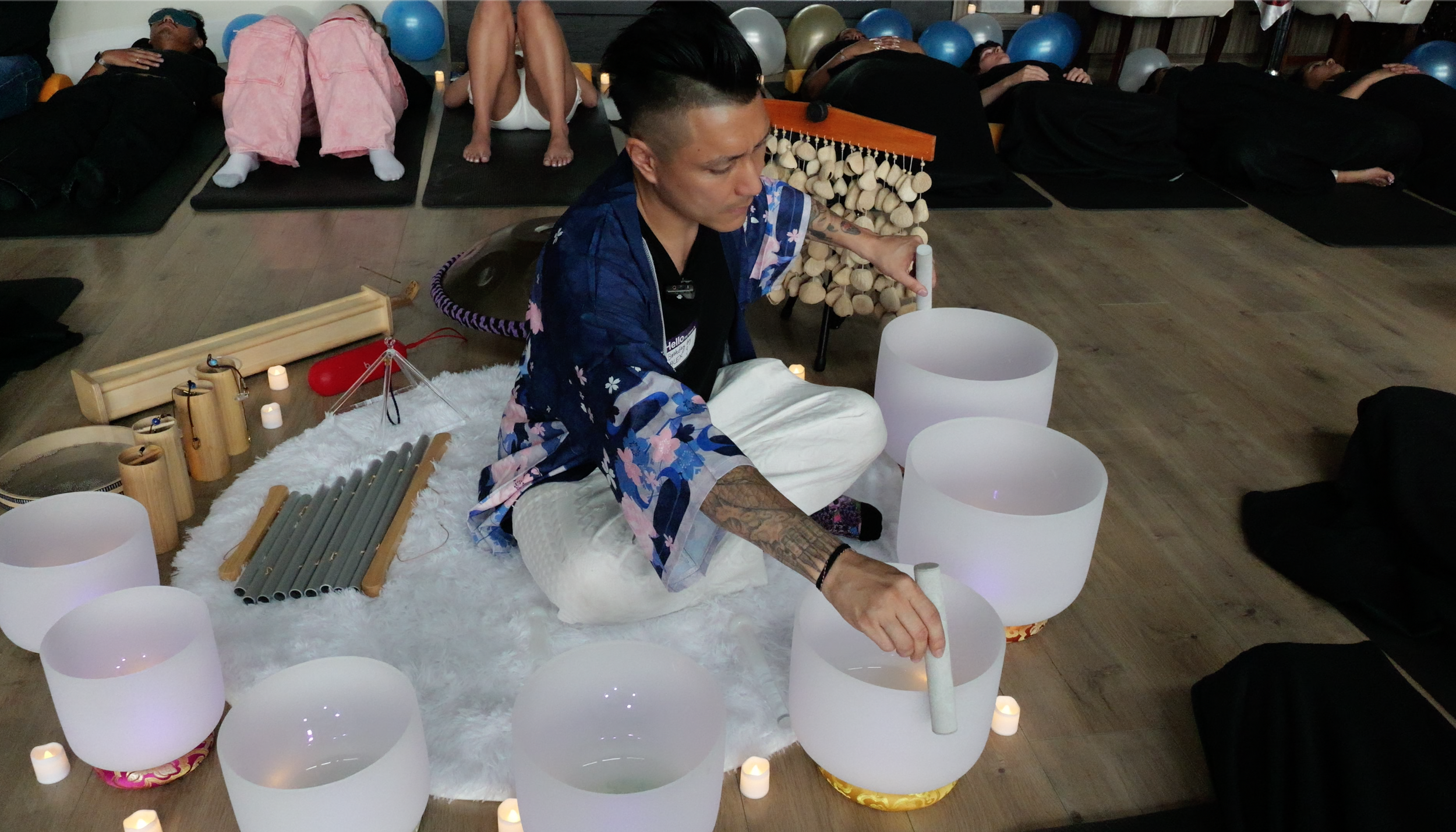 Sound bath facilitator Alex Ma playing the crystal sound bowls and kanji chimes during a private birthday party