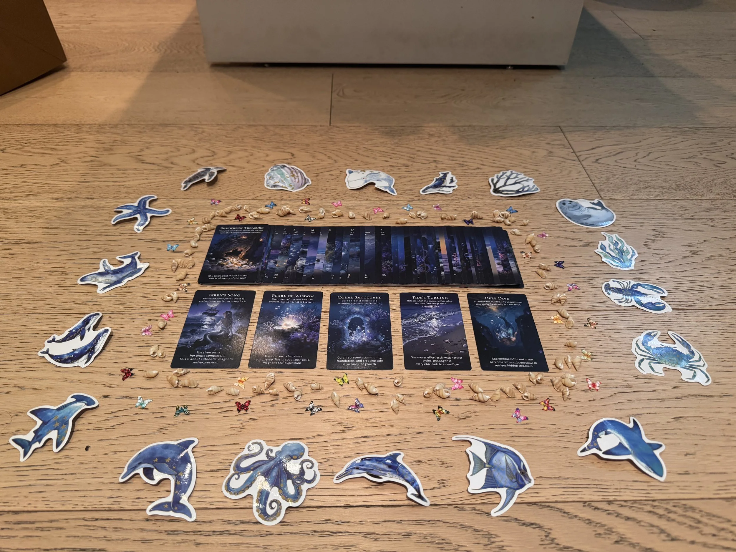 Some items including stickers, seashells, butterfly trinkets, and intention cards for a sea themed gift bag created for Olive & Piper Jewelry company's sound bath
