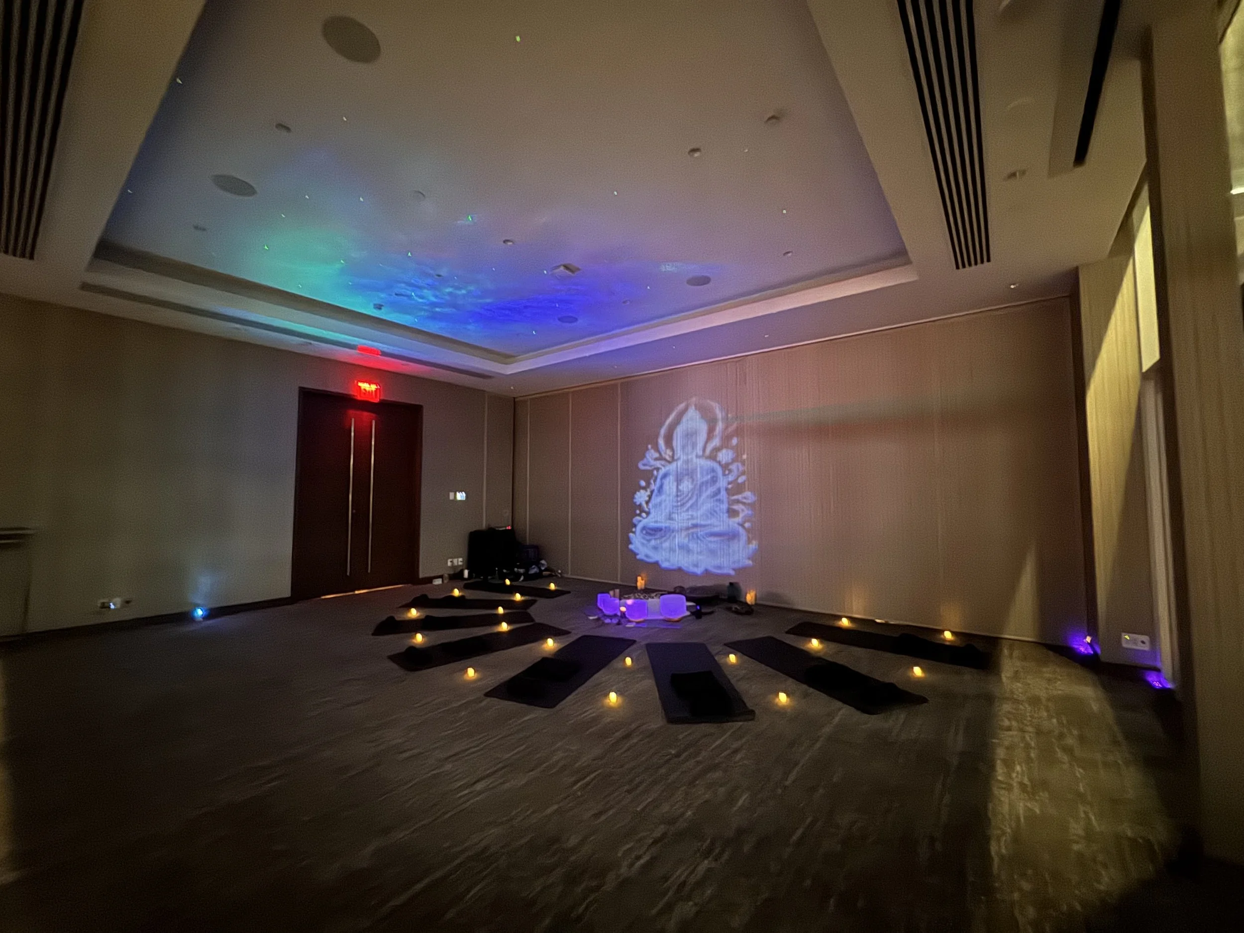 A Solar Soul Circle sound bath with ambient lighting, galaxy lights, a projected Buddha, candles and sound healing instruments.
