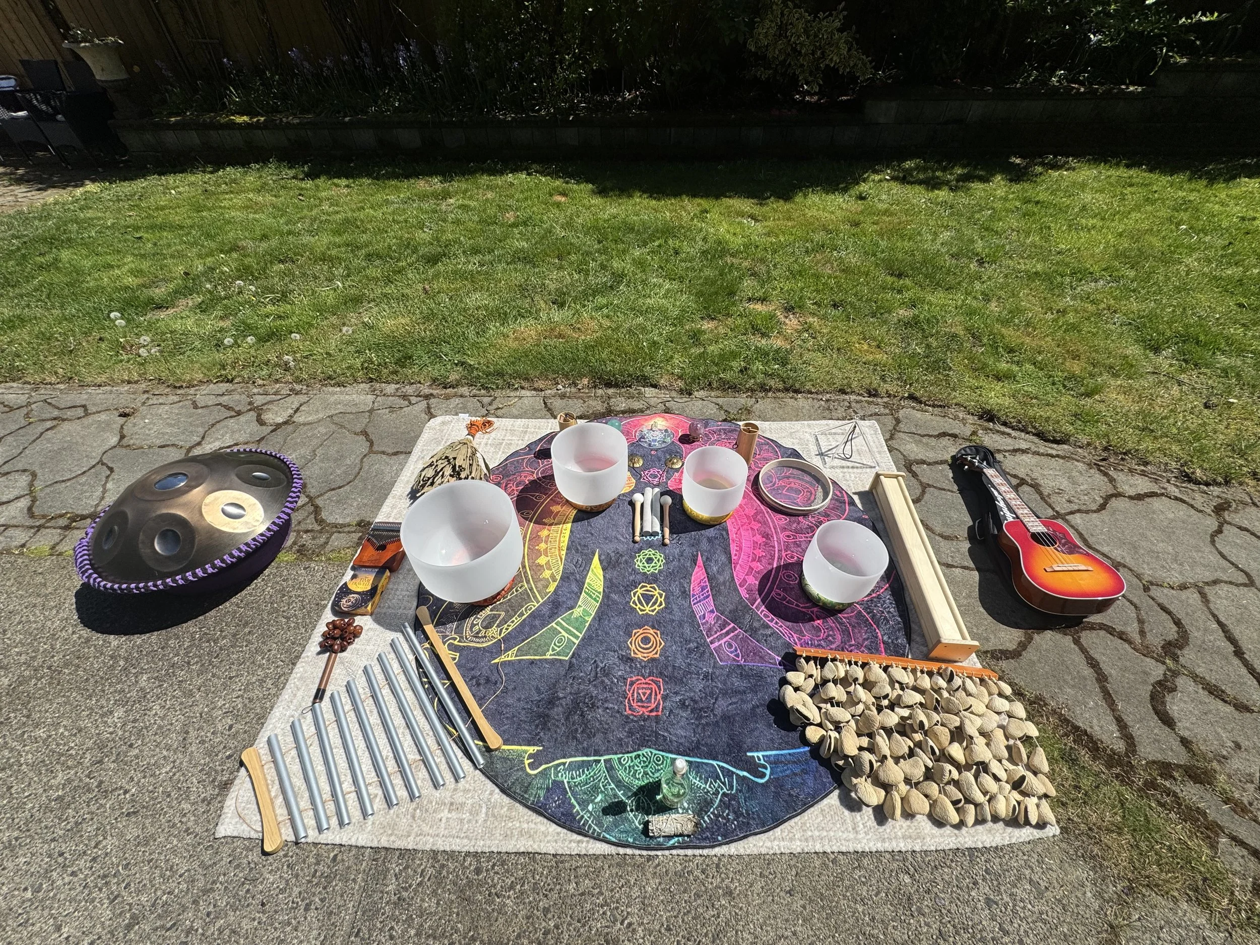 Outdoor birthday sound bath setup in Vancouver with crystal singing bowls, handpan, chimes, crystal pyramid, and calming instruments arranged for a private event by Solar Soul Circle.