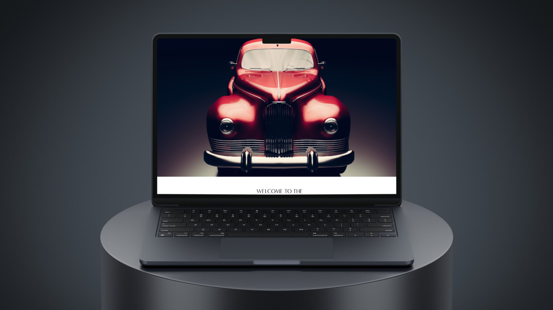 A laptop on a round table displaying an image of a vintage red car with the text 'Welcome to the' beneath it.