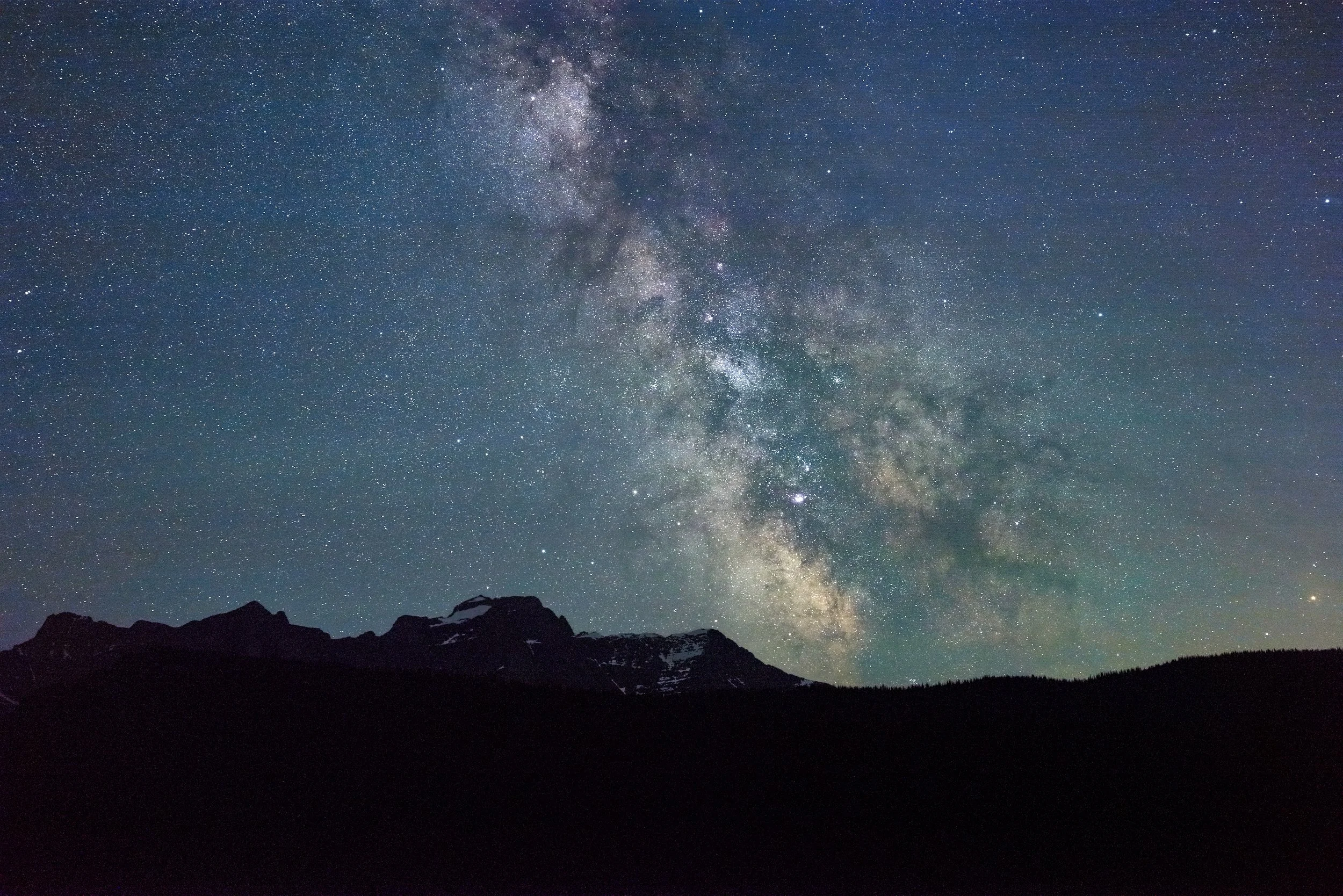 Milky Way over a mountain silhouette under a star-filled night sky.