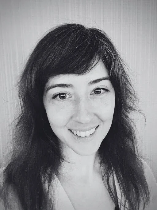 Black and white portrait of a woman with dark wavy hair, smiling and looking at the camera.