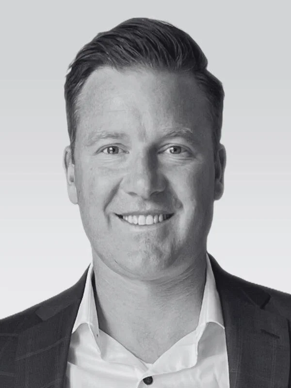 Black and white portrait of a smiling man in a suit and white shirt.