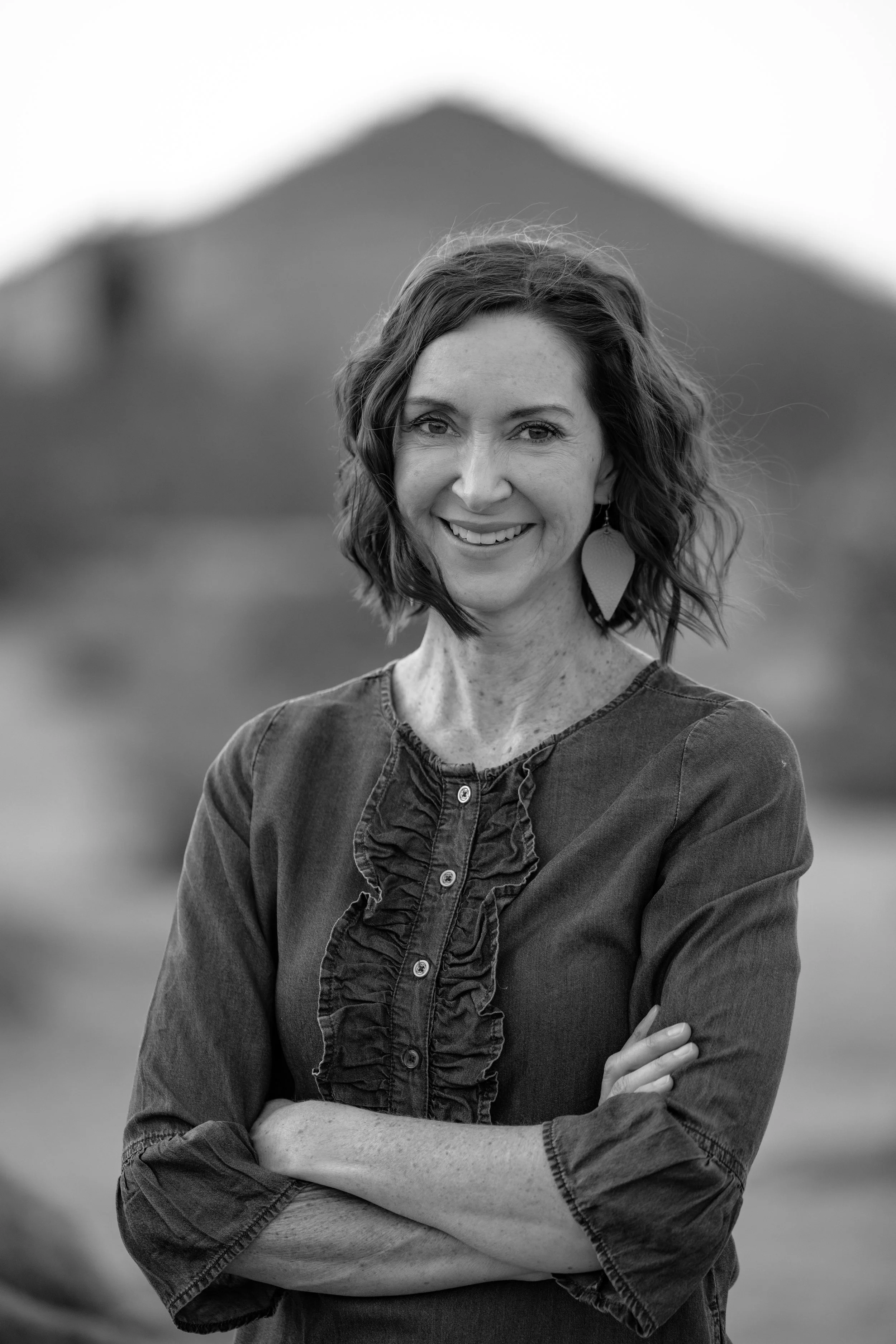 black and white image of a woman with short dark hair aginst a leafy background