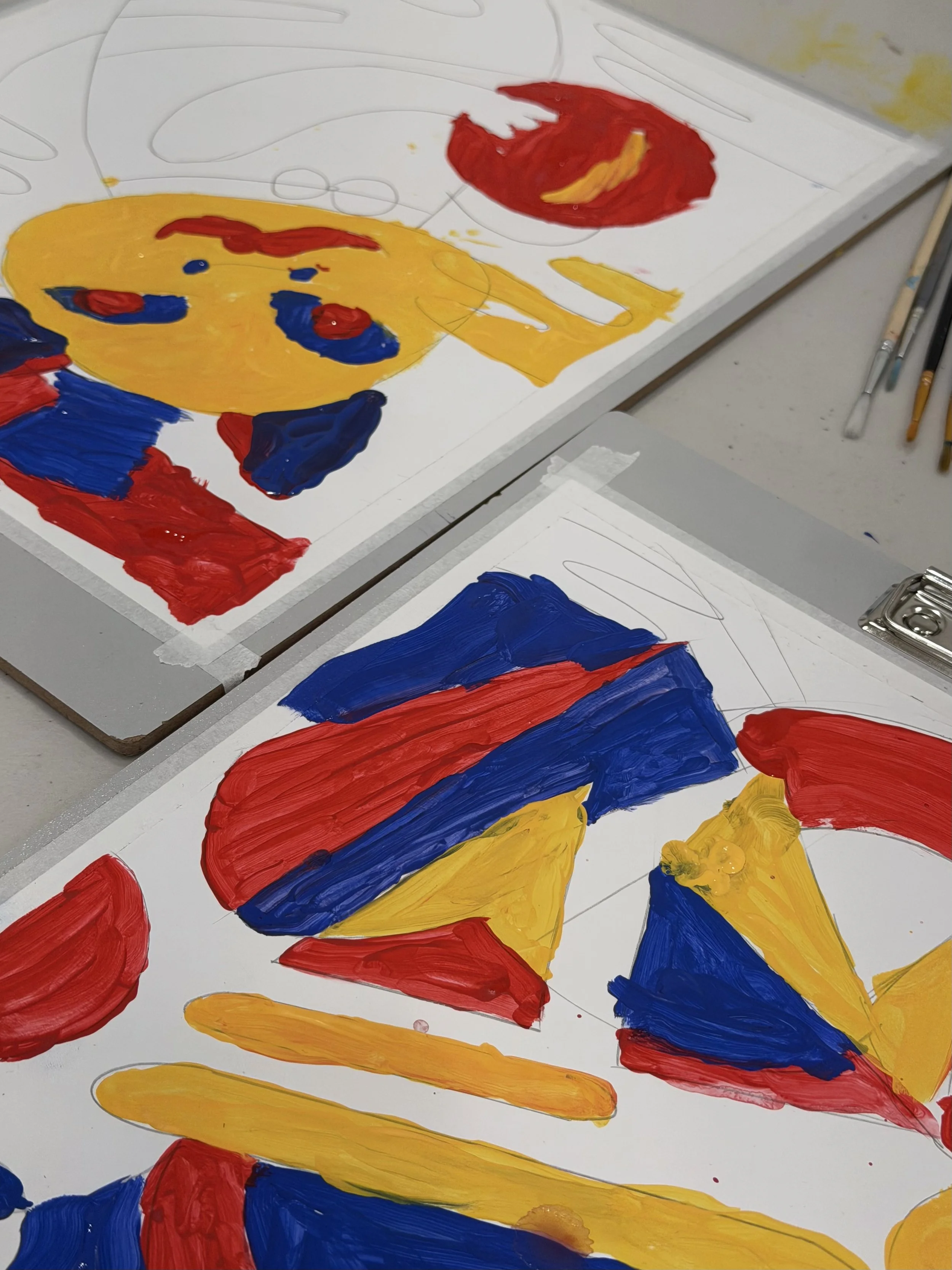 Children's finger-painted artwork featuring abstract shapes and colors including red, yellow, and blue on white paper.