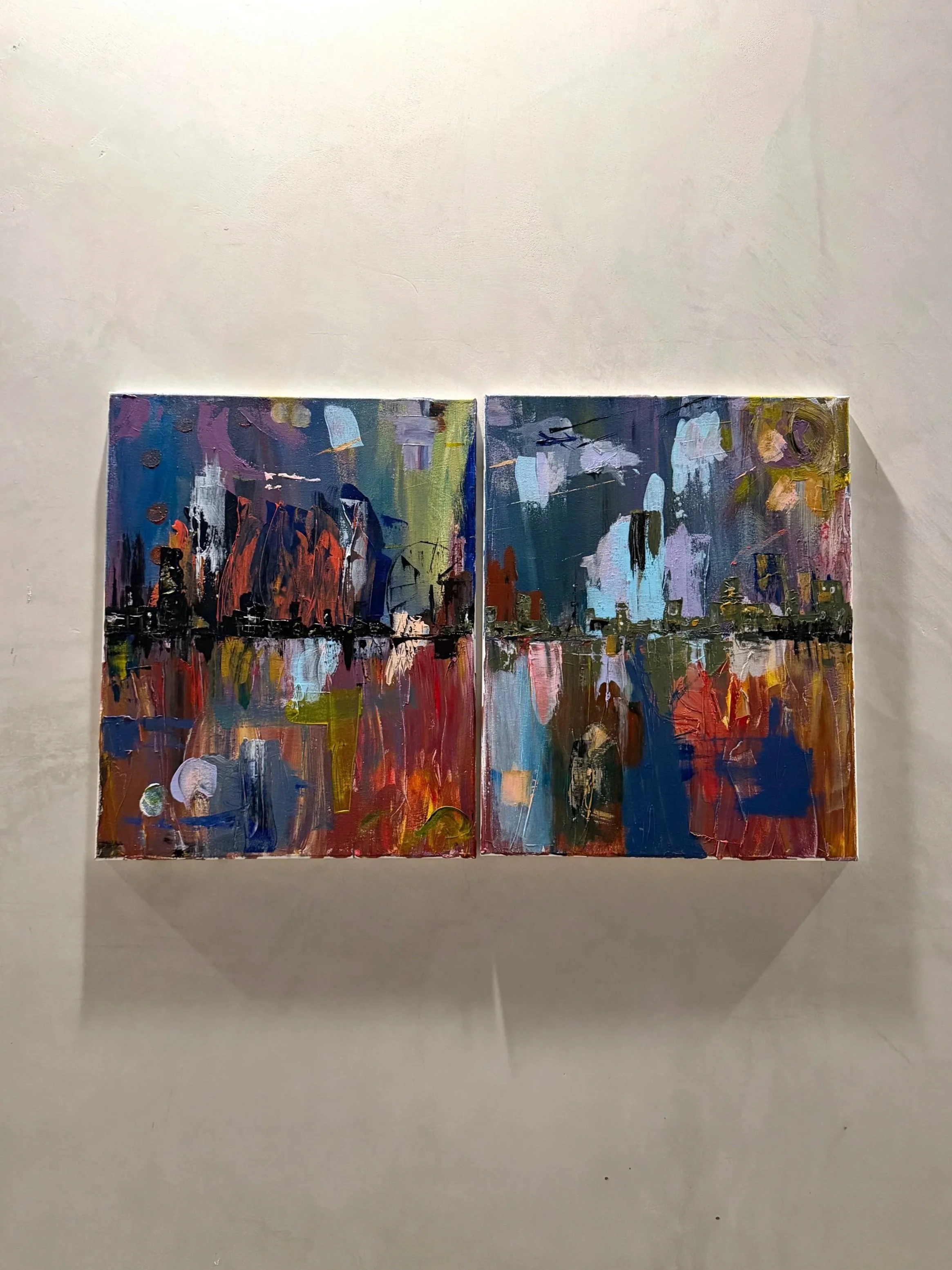 Two abstract colorful paintings on a wall with a neutral background.