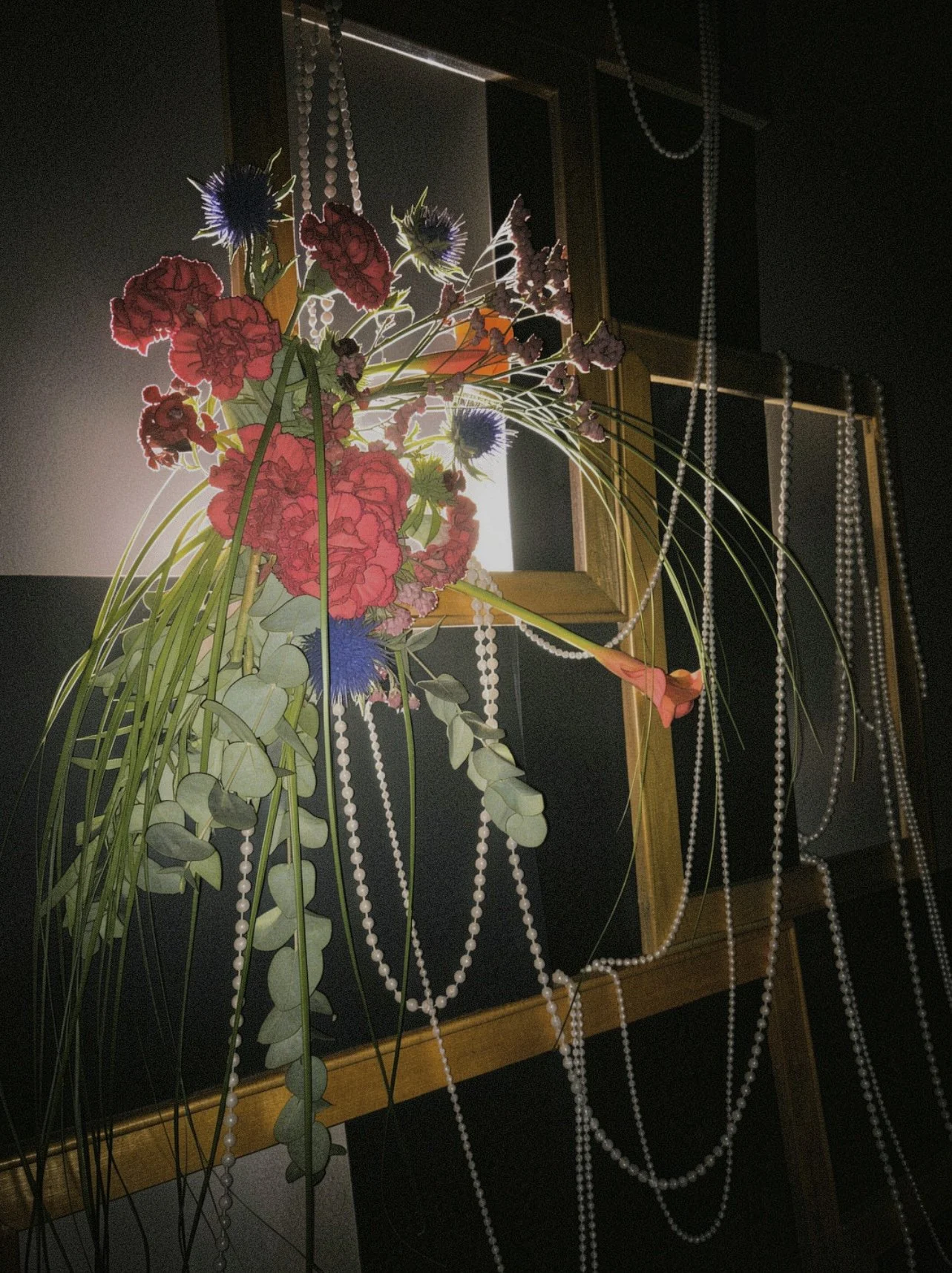 A floral arrangement featuring pink and purple flowers with greenery, displayed outdoors near windows with pearl-like bead decorations hanging around.