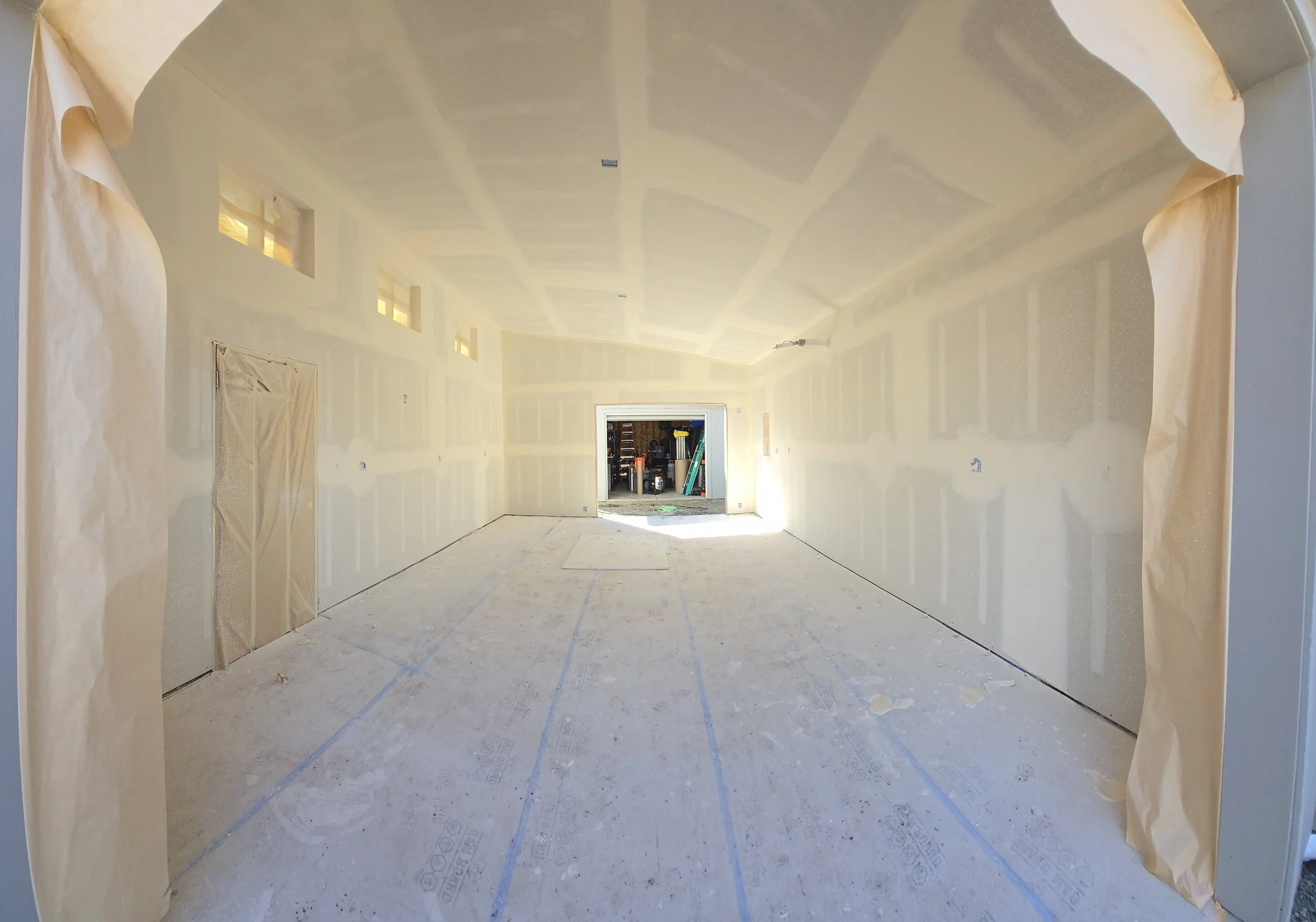 Completed detached garage interior in Eugene’s Friendly Area, featuring smooth drywall finishes with a light orange peel texture and precise four-way square window returns, ready for paint.