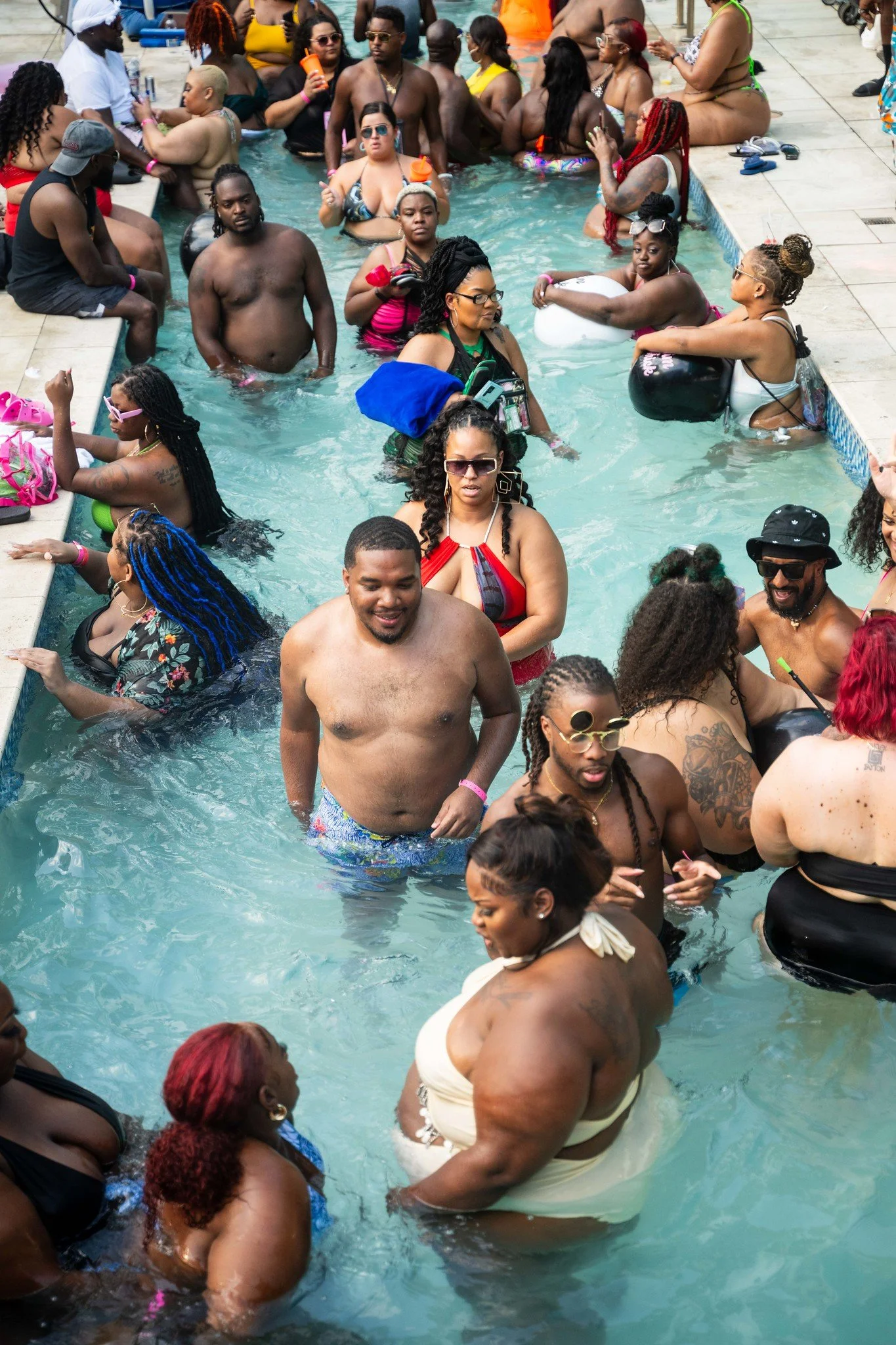 A crowded pool party with diverse people enjoying and socializing in the swimming pool.