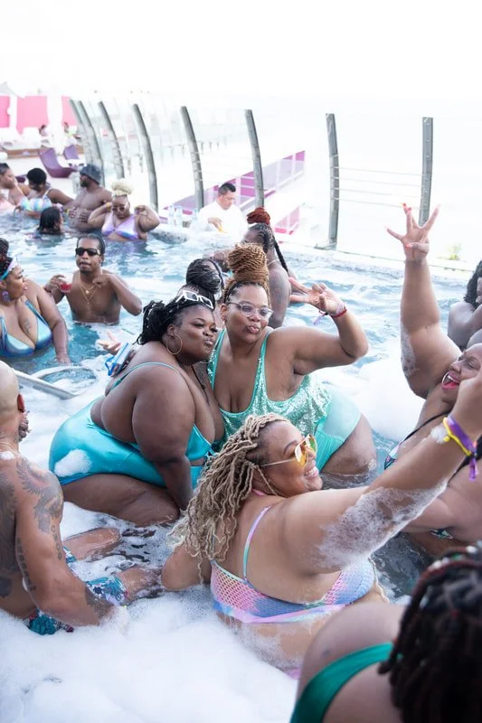 People enjoying a pool party on a cruise ship, some dancing and posing for the camera.