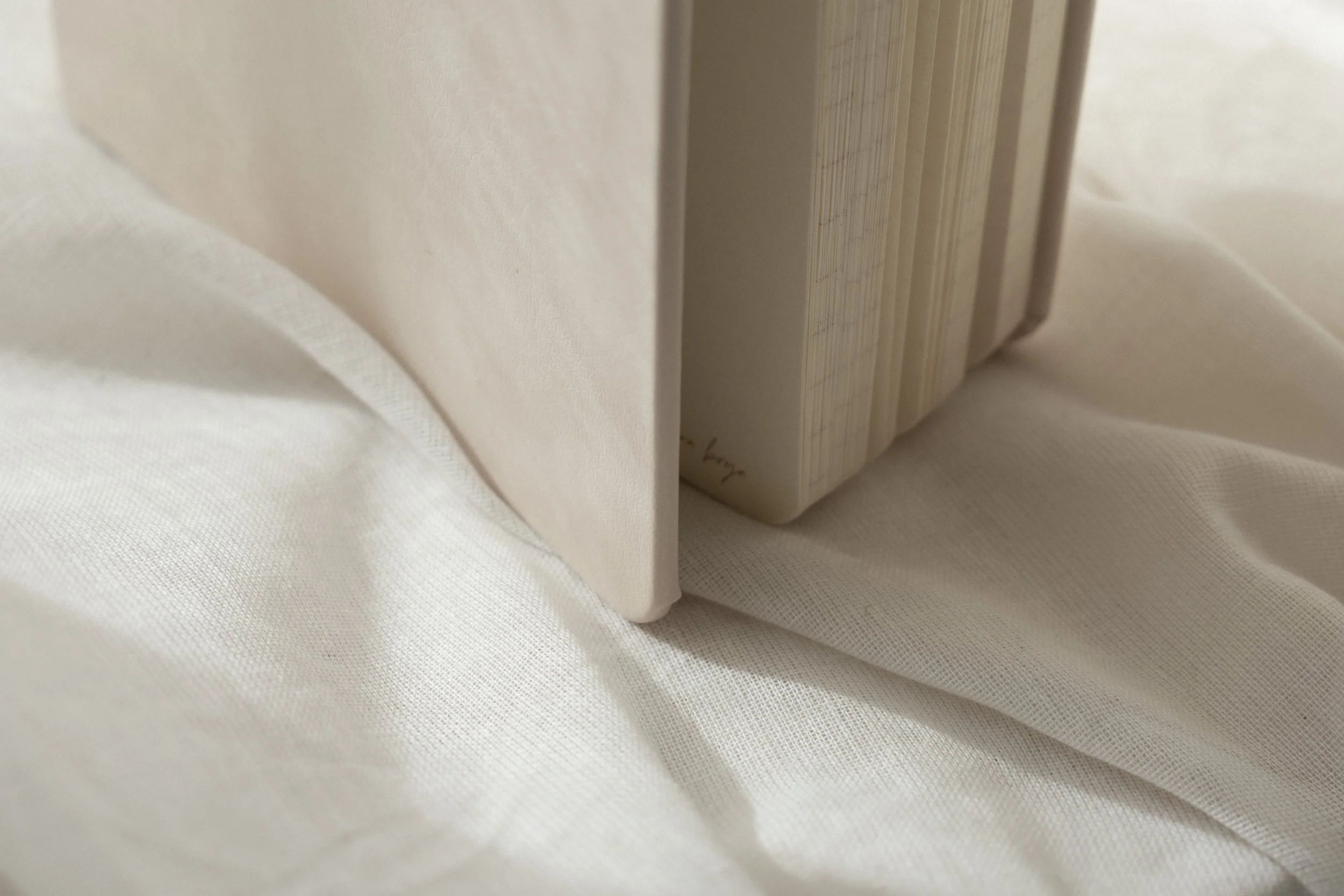 Close-up of a white hardcover vegan leather planner with a plain cover, standing upright on a white fabric surface.
