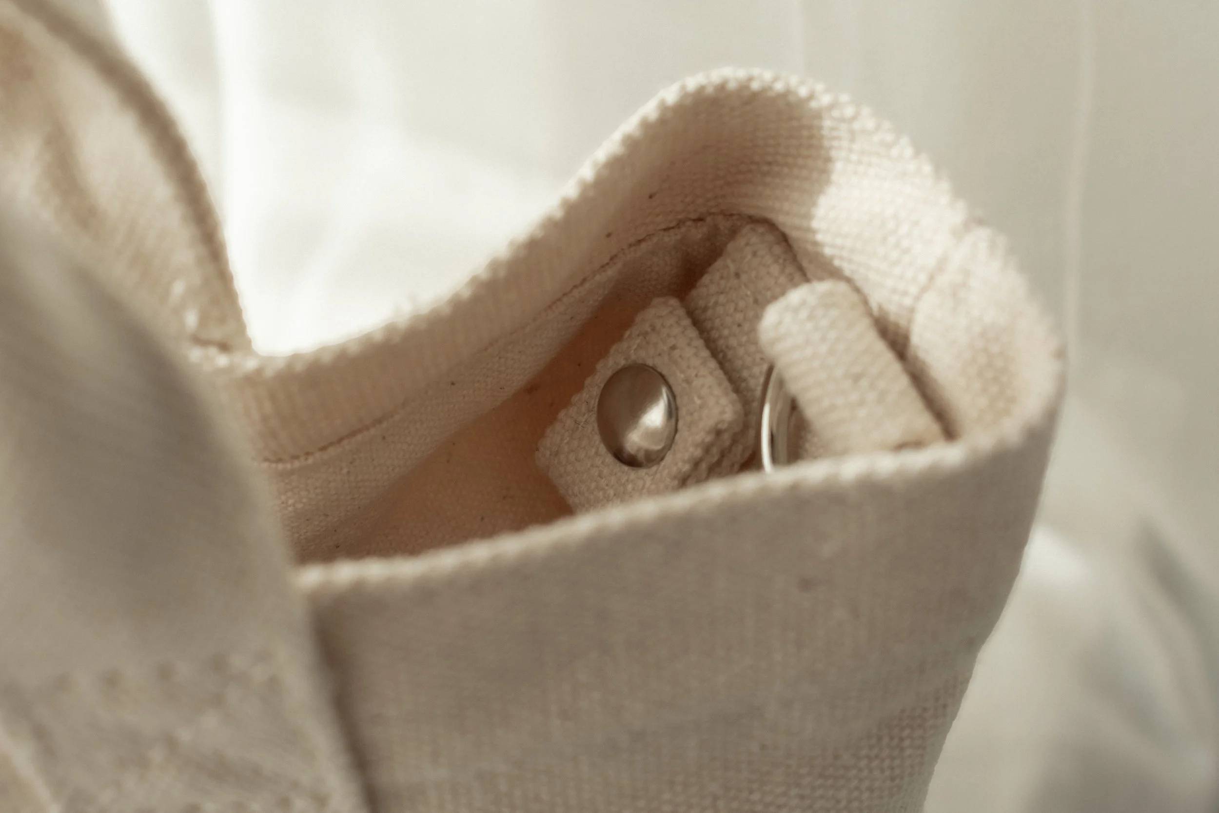 Close-up of a beige fabric bag with metal snap button key clip inside.