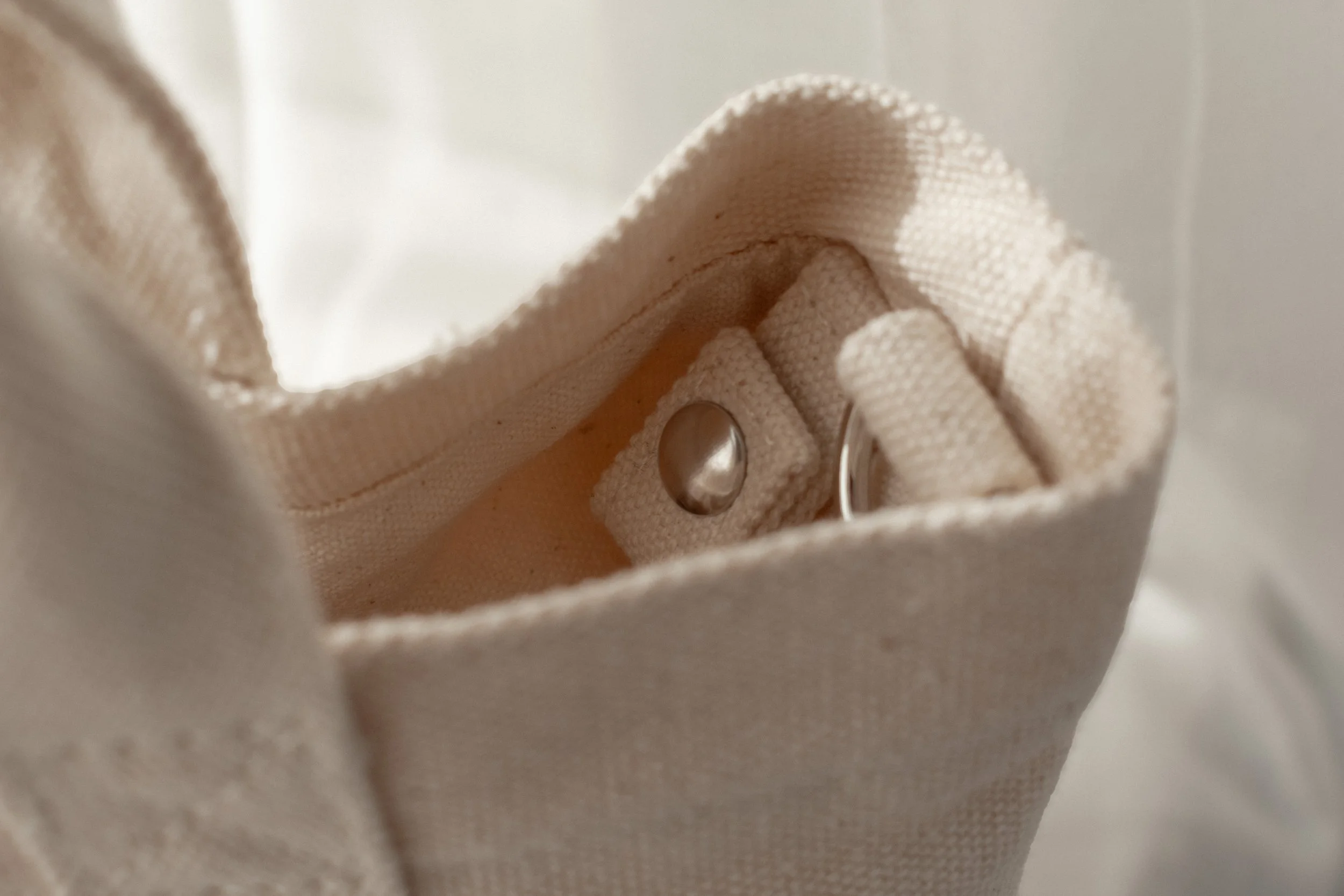 Close-up of a beige fabric bag with metal snap button key clip inside.