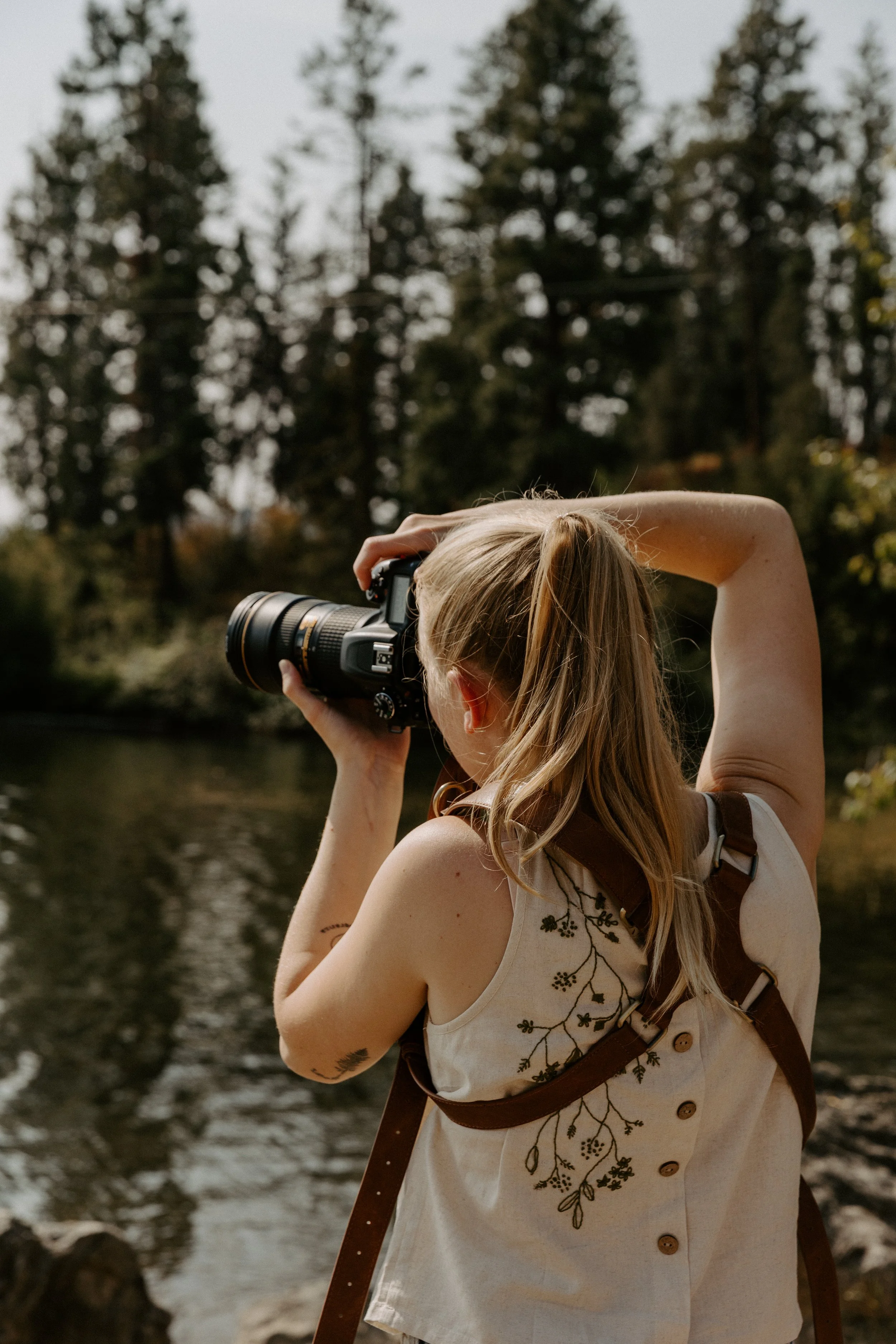 woman taking a photo of lake and trees