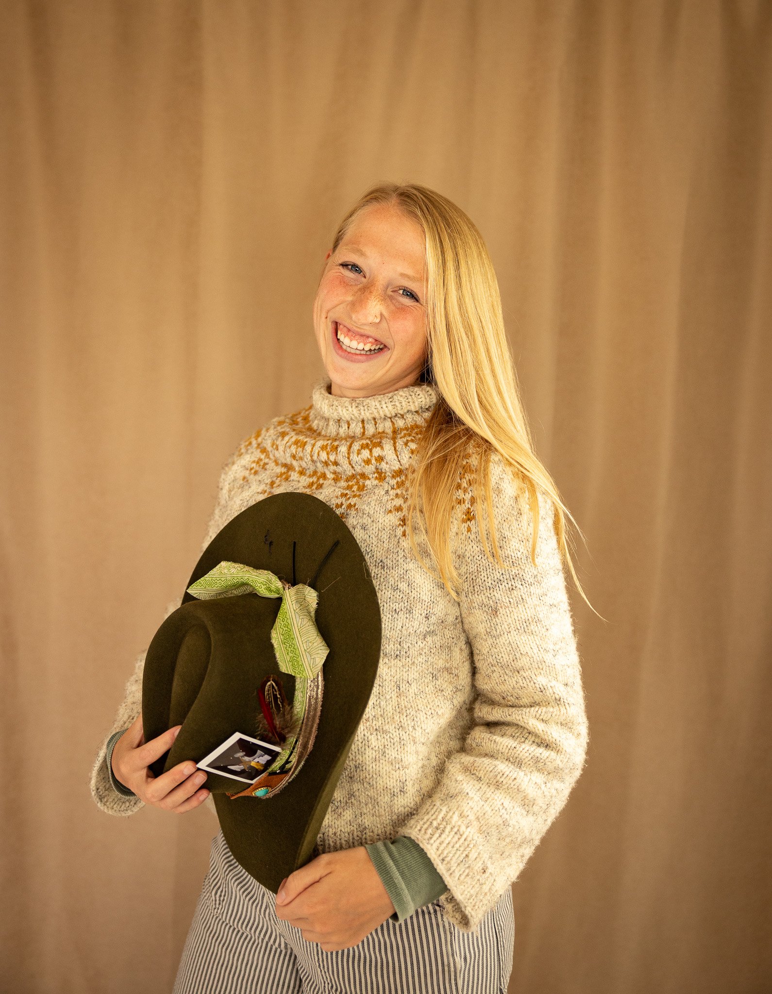 woman smiling and holding hat