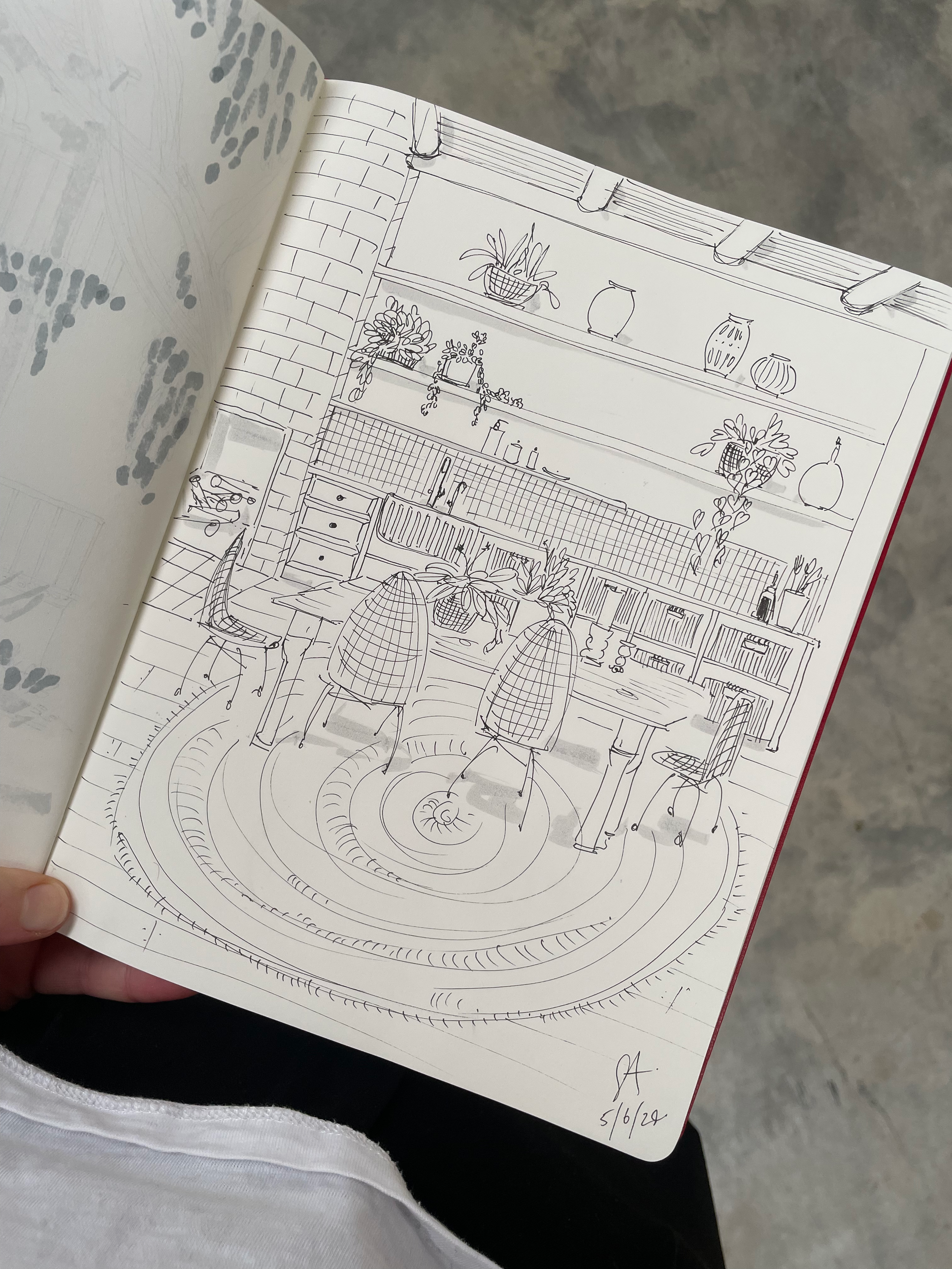 A sketch of a cozy kitchen and dining area with open shelving, potted plants, vases, and kitchen utensils, along with a round rug and wicker chairs around a dining table.