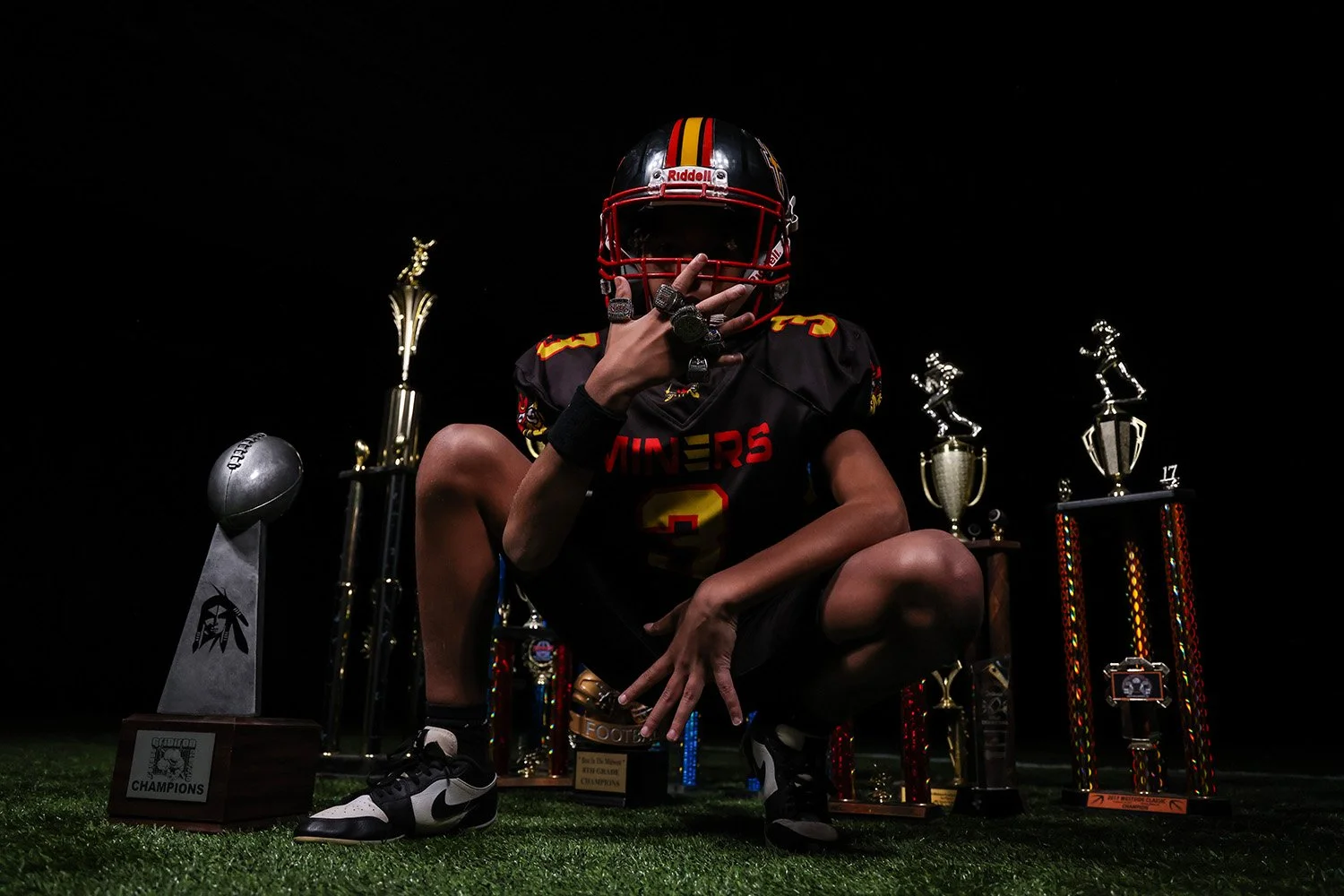Midwest Miner football player with championship rings showing strength