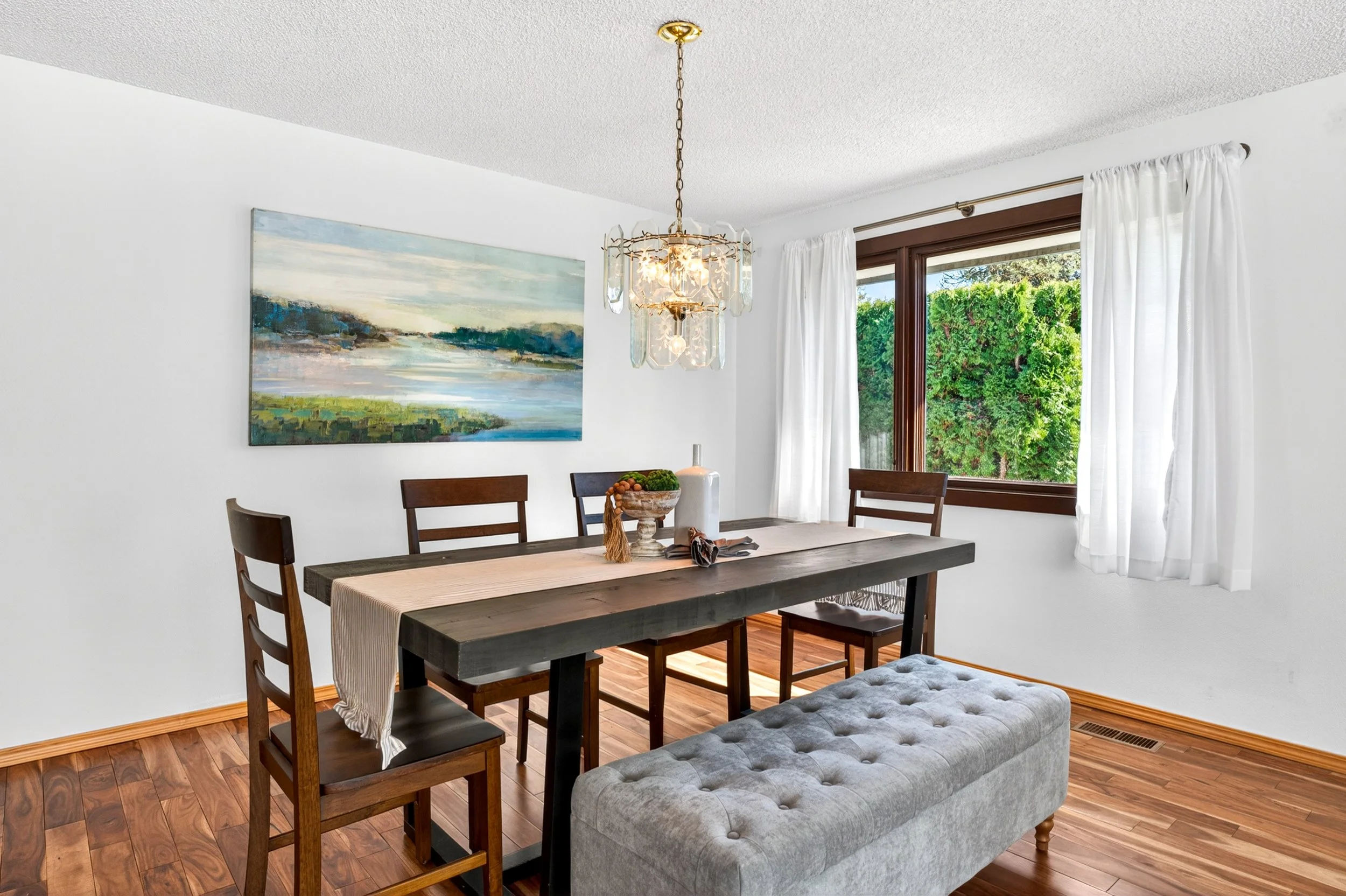 Spokane Real Estate Photography -  A dining room with a wooden table, six chairs, and a tufted bench. 