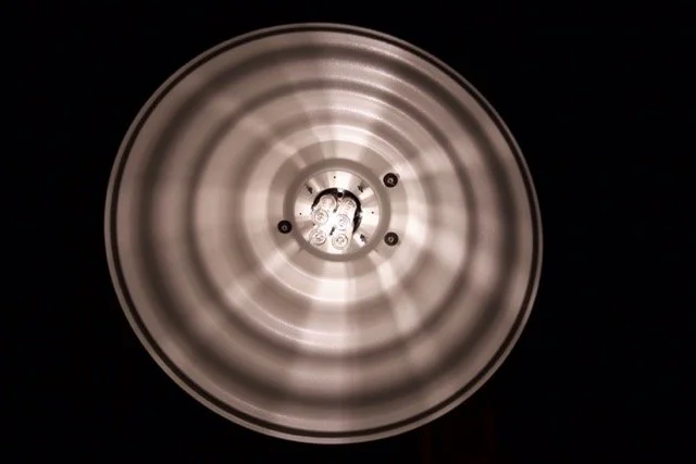 Close-up of the interior of a round ceiling light fixture showing a lightbulb and reflective surfaces.