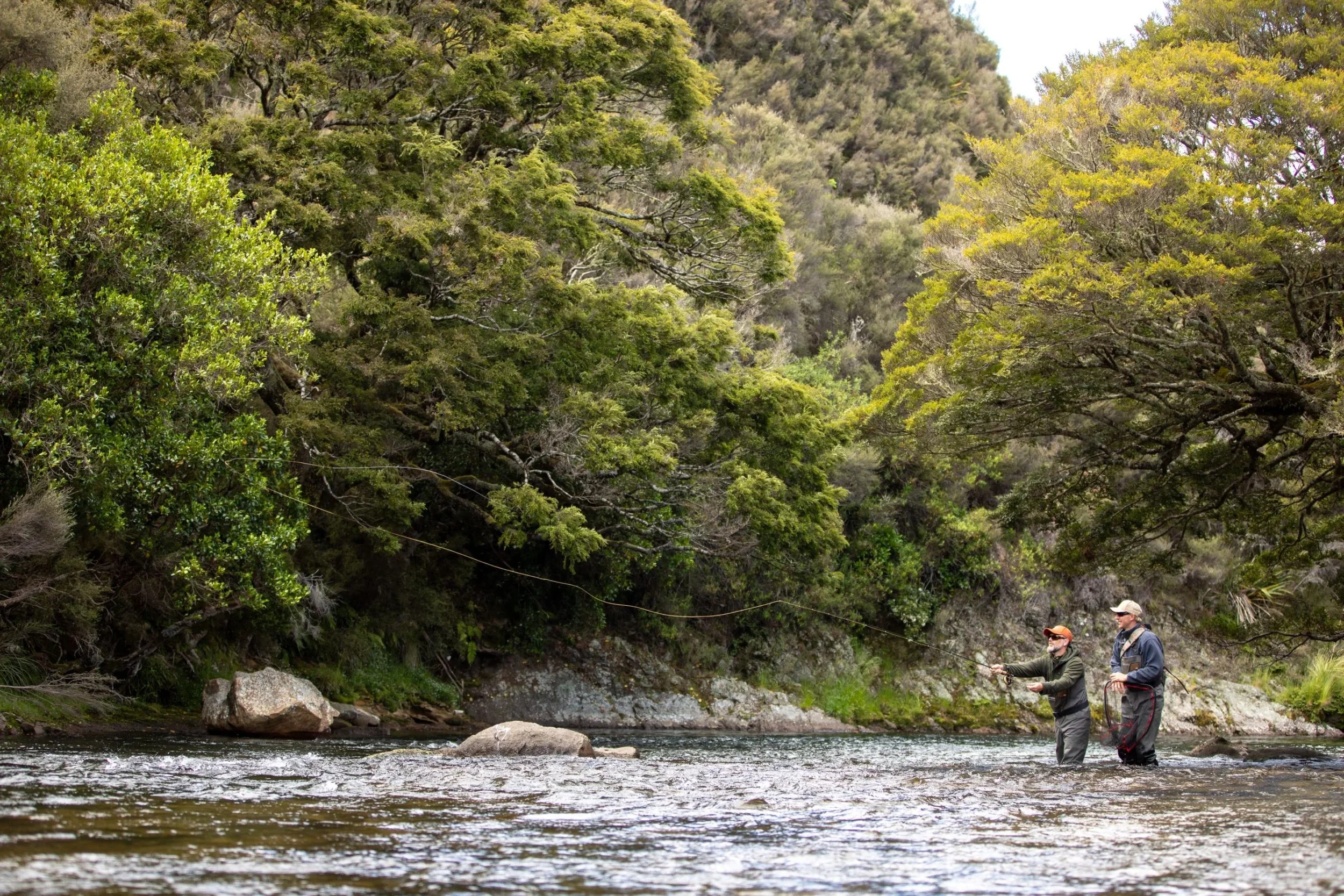 Fly fisherman casting in shaded river pool near Stonefly Lodge