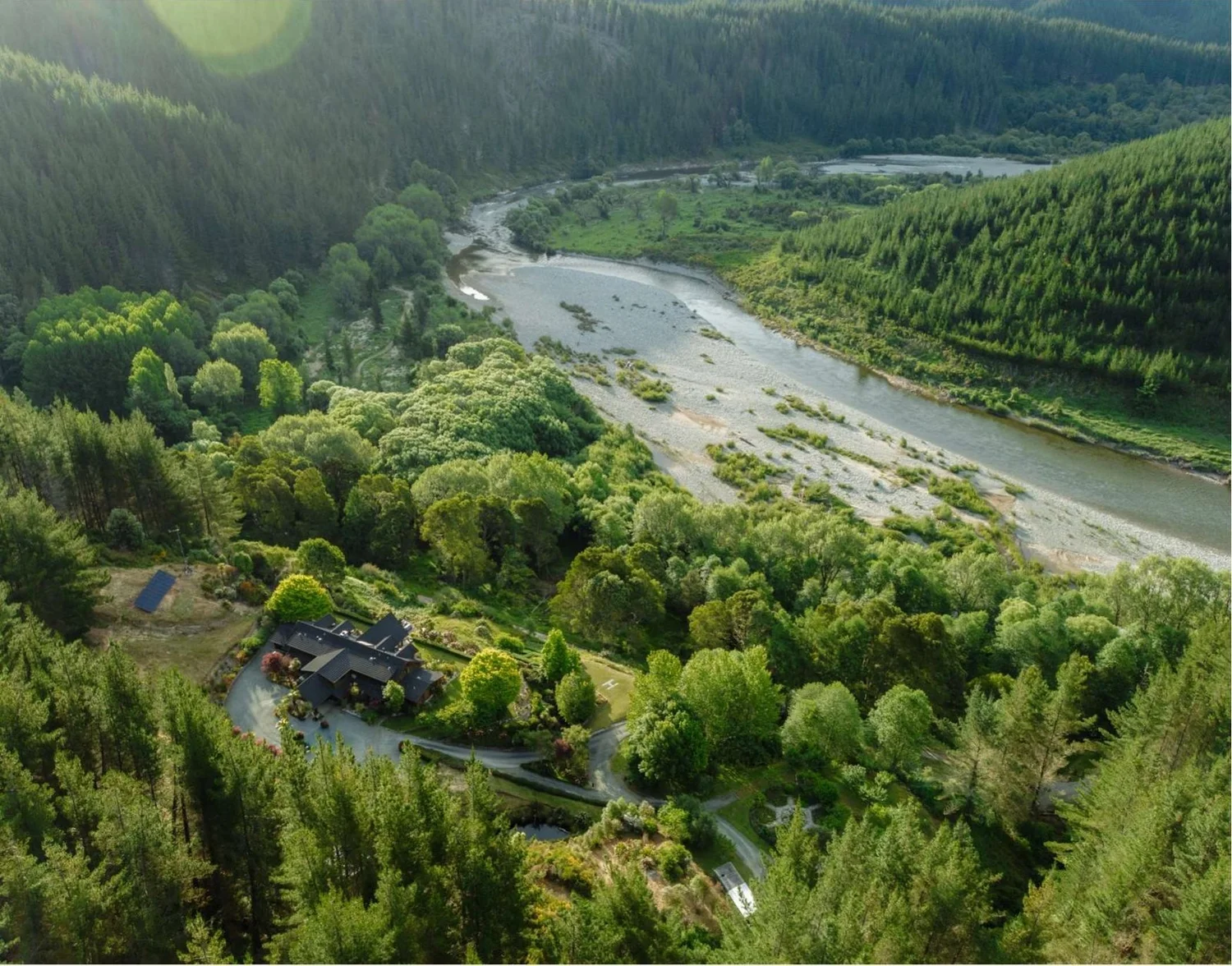 Aerial view of Stonefly Lodge among forest above a bend in the Motueka River