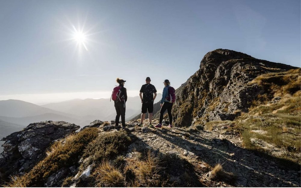 Three hikers pausing on a rocky ridge in Kahurangi National Park